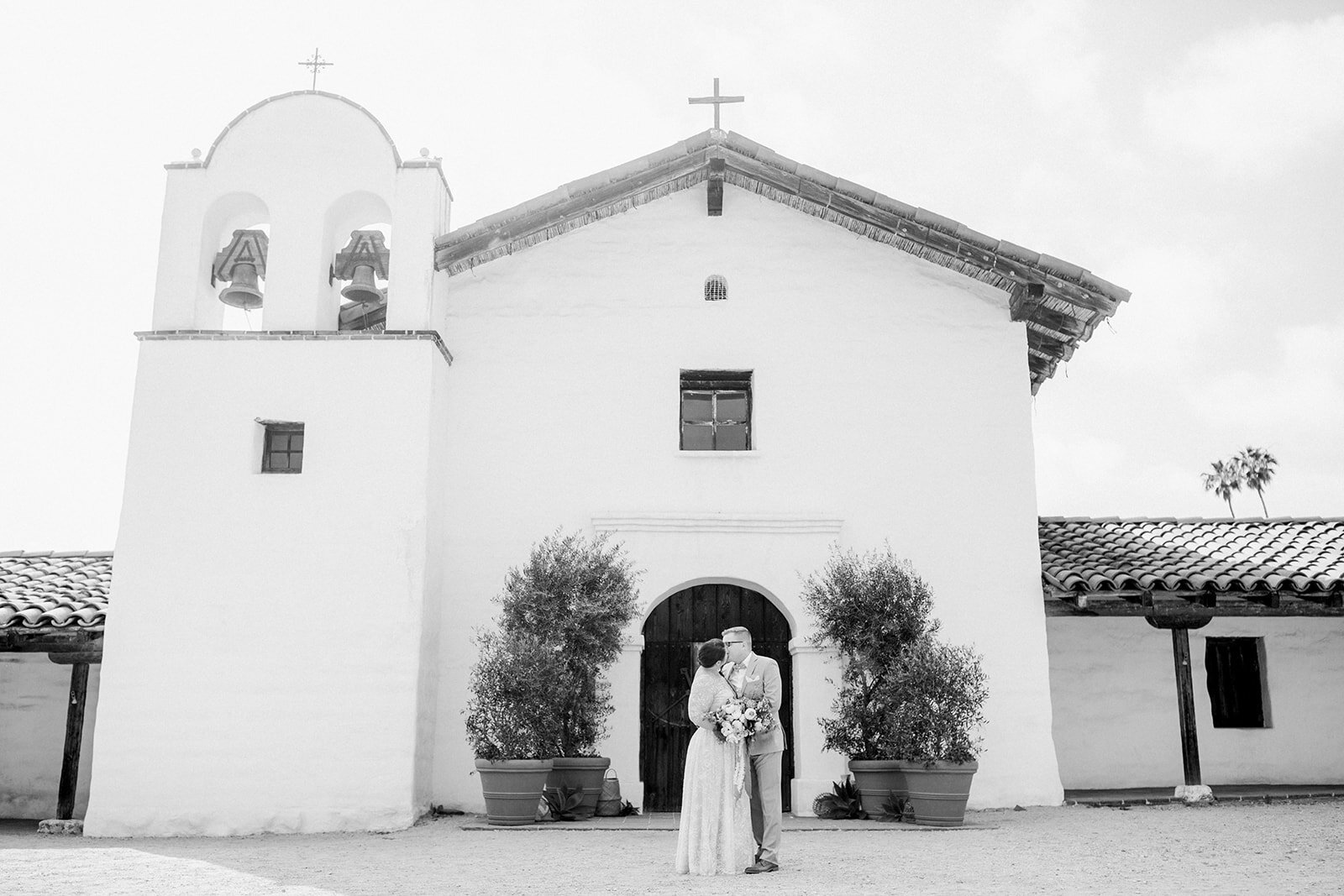 www.santabarbarawedding.com | El Prisidio | Anna Delores | Jill &amp; Co Events | TOAST | Coco Rose Design | Marchesa Notte | Bride and Groom Share A Kiss Outside the Venue