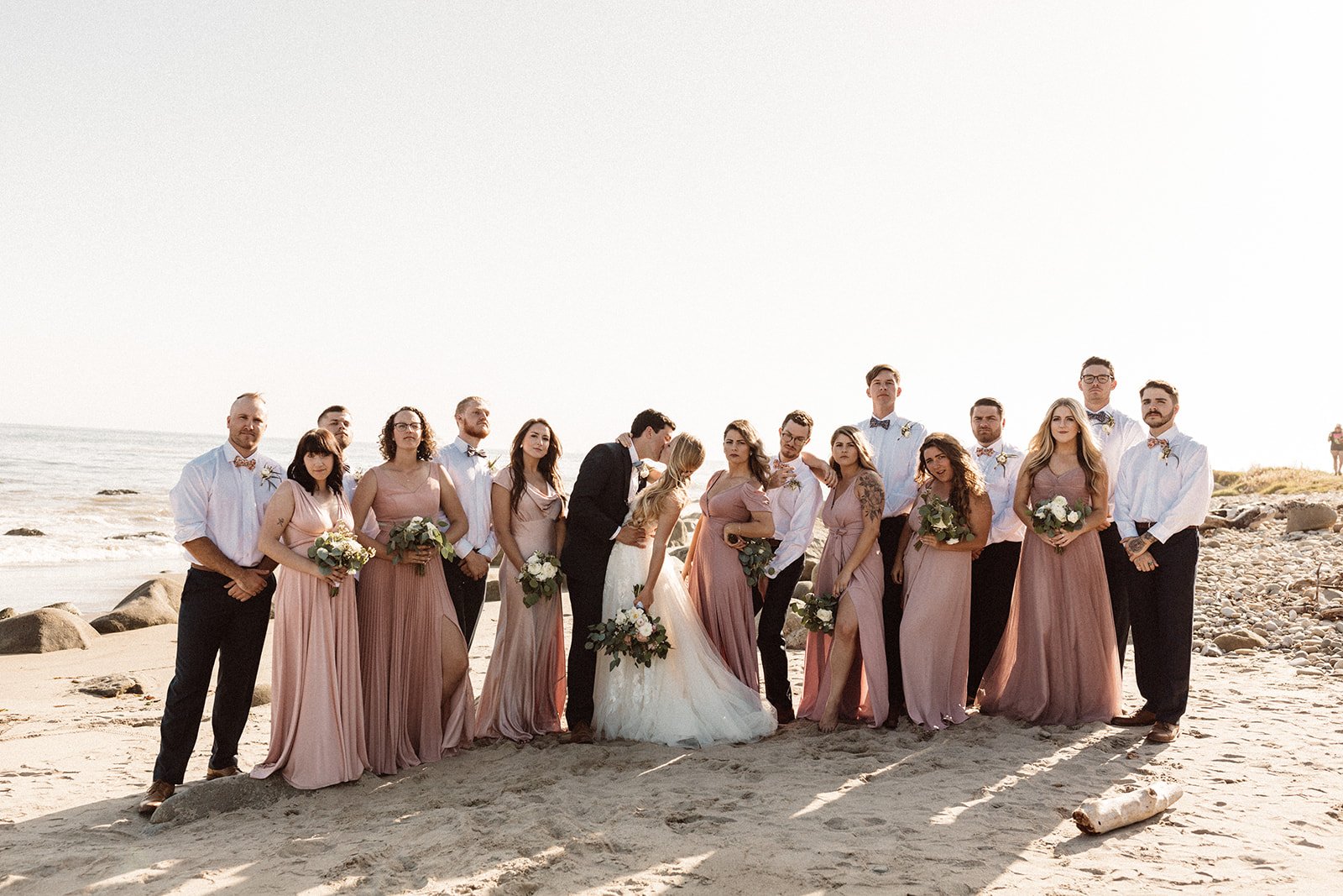 www.santabarbarawedding.com | Isabella Griffith Photography | El Capitan State Beach | KB Events | Alexis Ireland Florals | Bride and Groom Kiss Surrounded by Bridal Party 