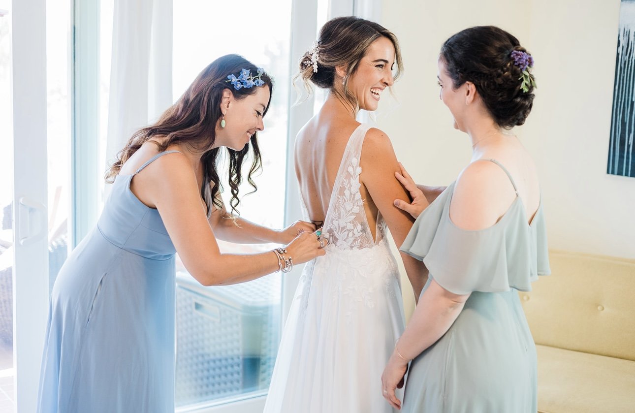 www.santabarbarawedding.com | RG Photography | Events by Fran | Godric Grove | Bridesmaids Helping Bride Put on Dress