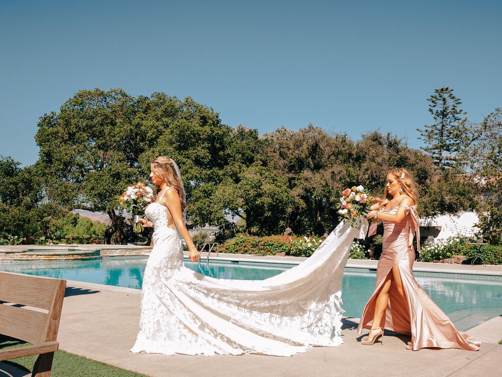 www.santabarbarawedding.com | Events by Fran | Quail Ranch | Scott Andrew Co. | Hair by Samantha Walters | Bella Bridal Couture | Bridesmaid Carrying Bride’s Train Walking by Pool