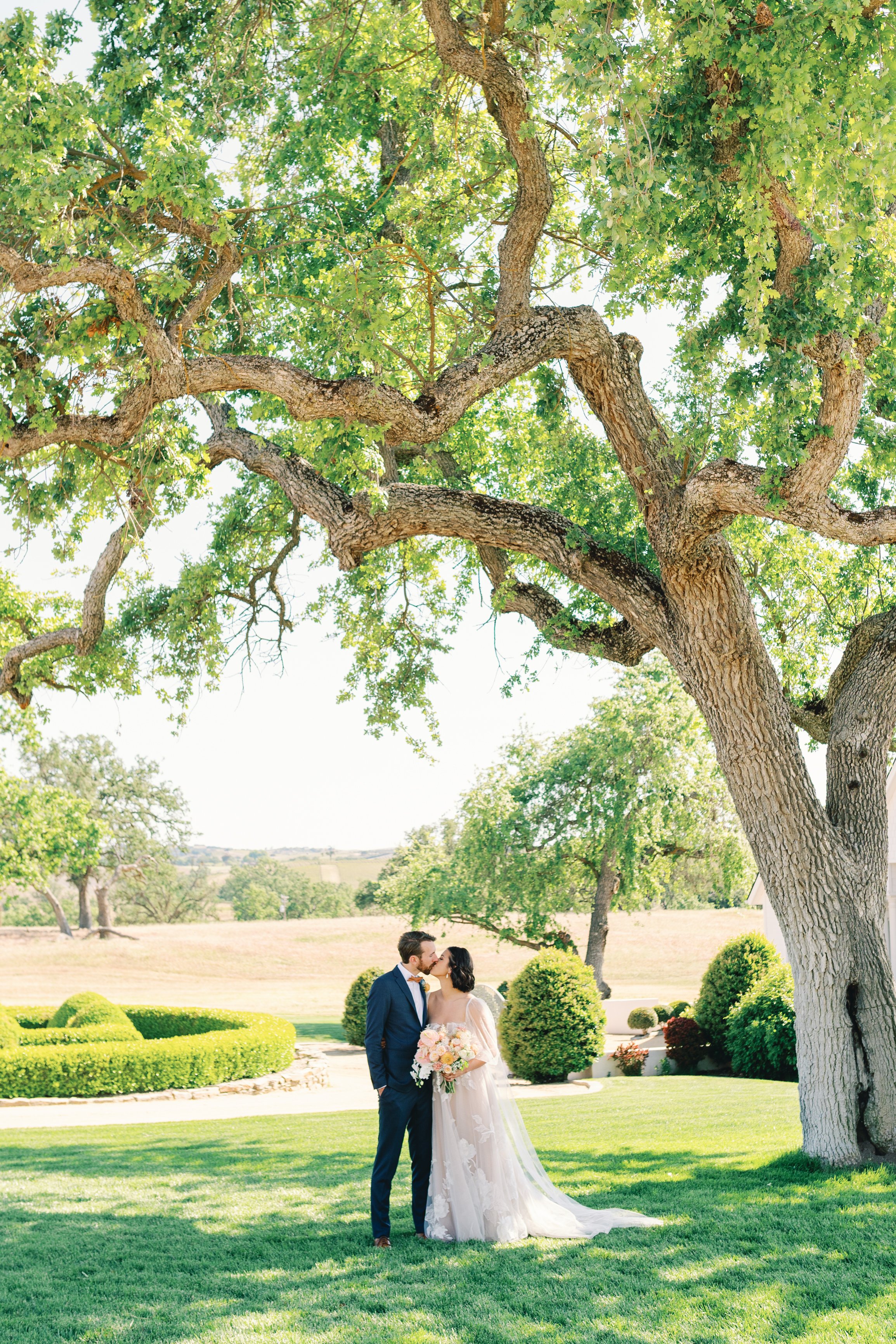 www.santabarbarawedding.com | Augusta Ottillia Photography | Megan Rose Events | Fallen Oaks Estate | Brooke Edelman | Meagan Fondren | Bride and Groom Kissing Under Oak Tree