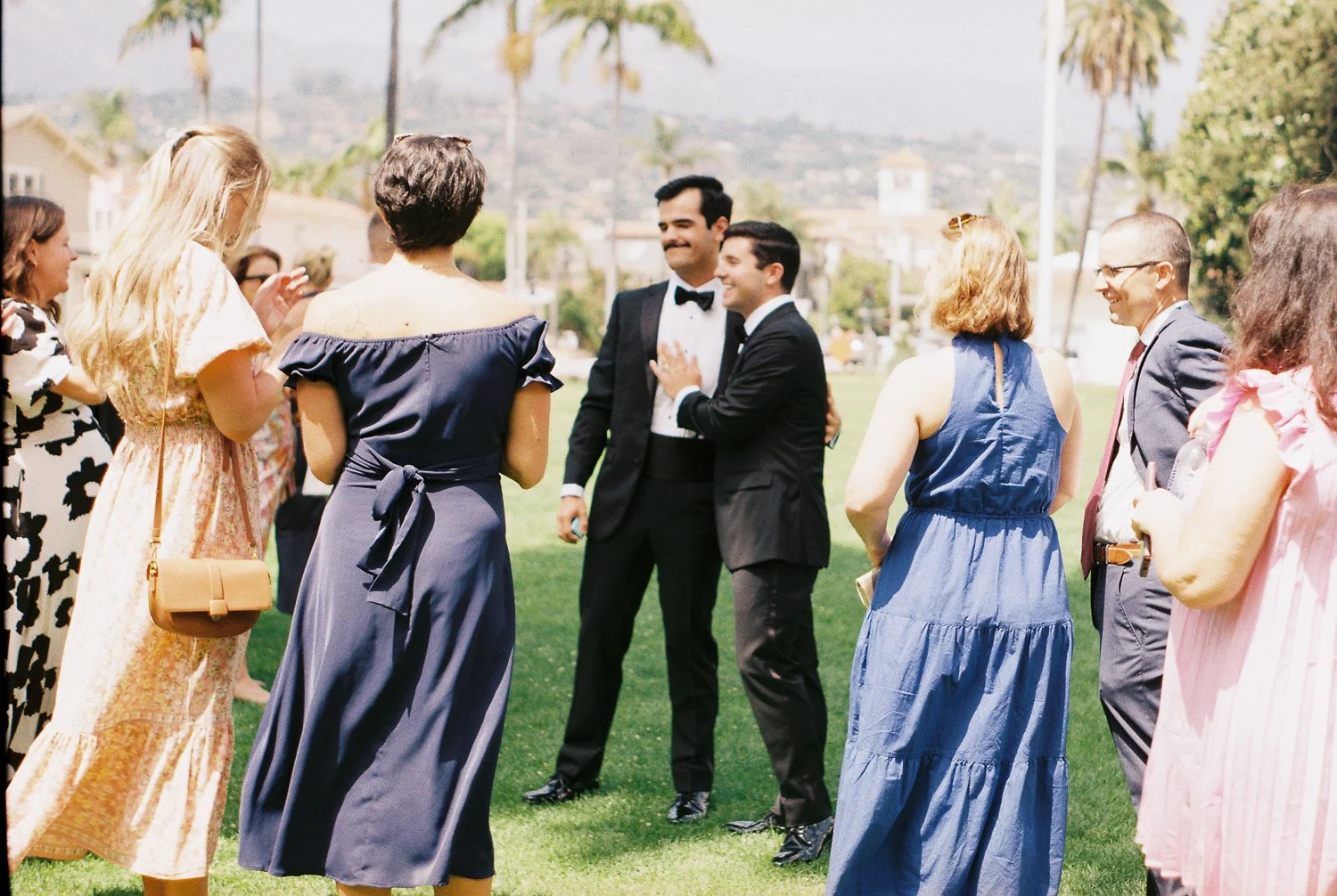 Grooms embracing surrounded by guests