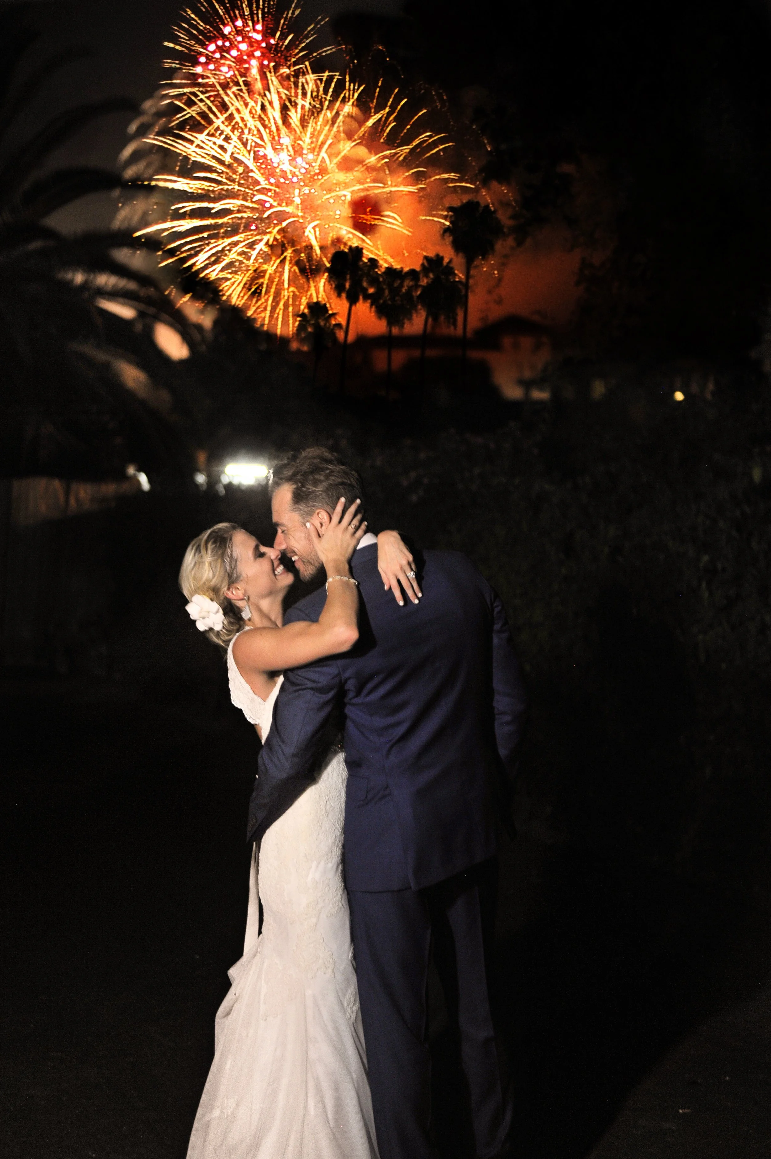 Bride and groom kissing during firework show