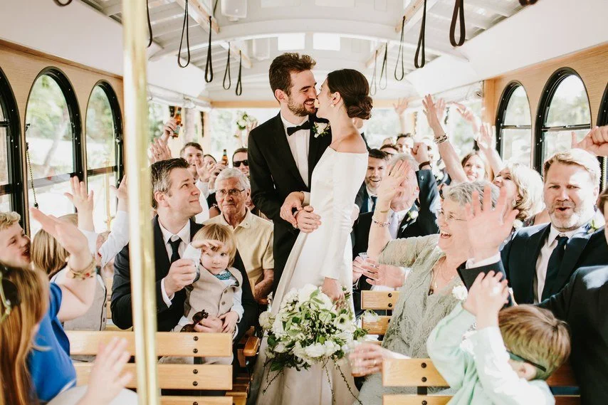 Couple embrace on Santa Barbara trolley surrounded by guests