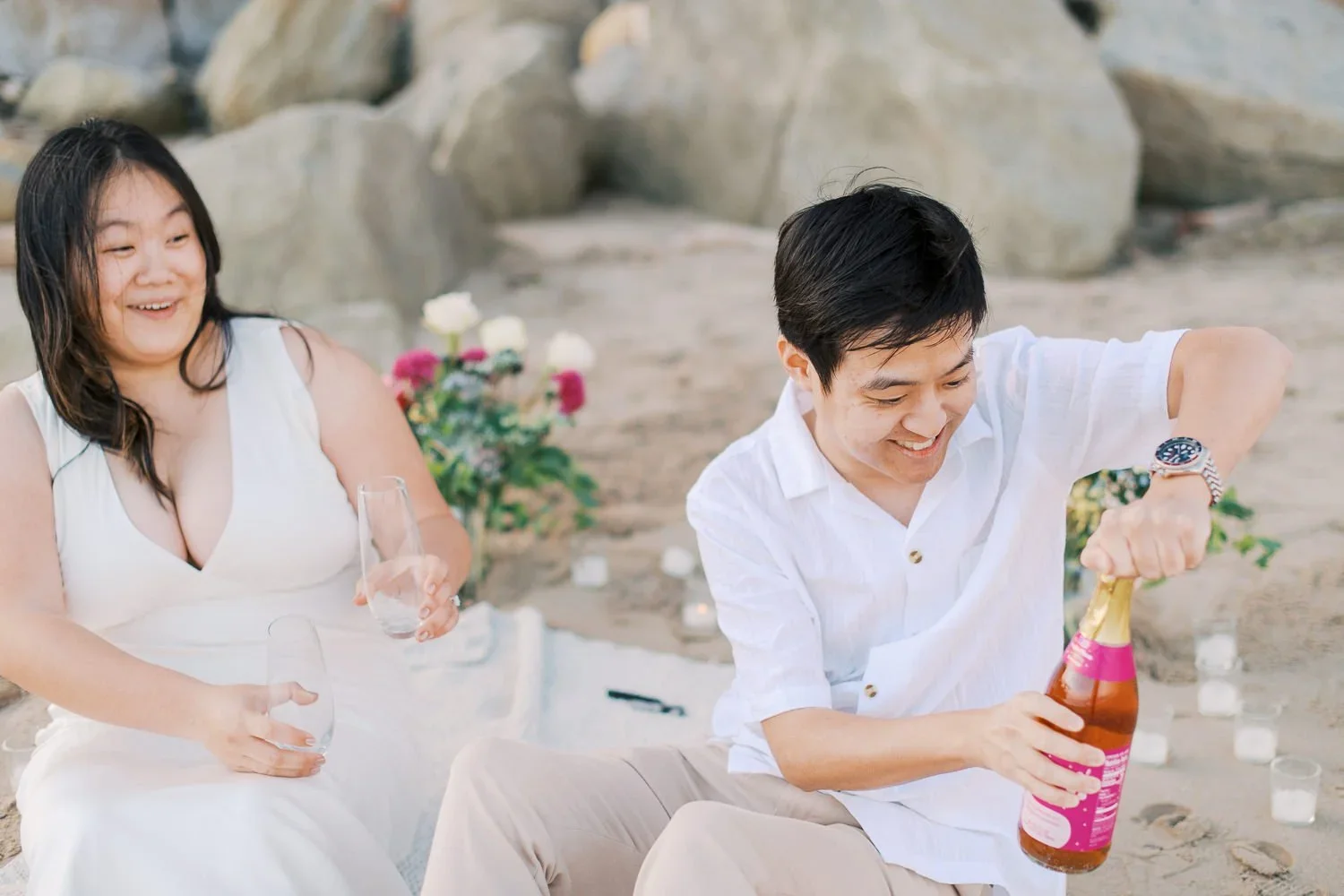 Couple popping bubbly at beach proposal