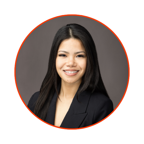 Portrait of a smiling woman with long black hair, wearing a dark blazer, against a gray background, outlined with a red circle.