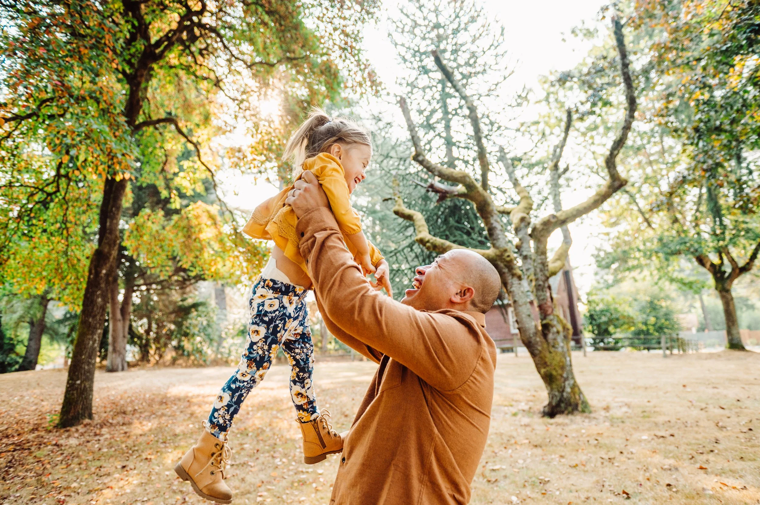 Father tossing daughter in the air at family photos in Kirkland in the fall
