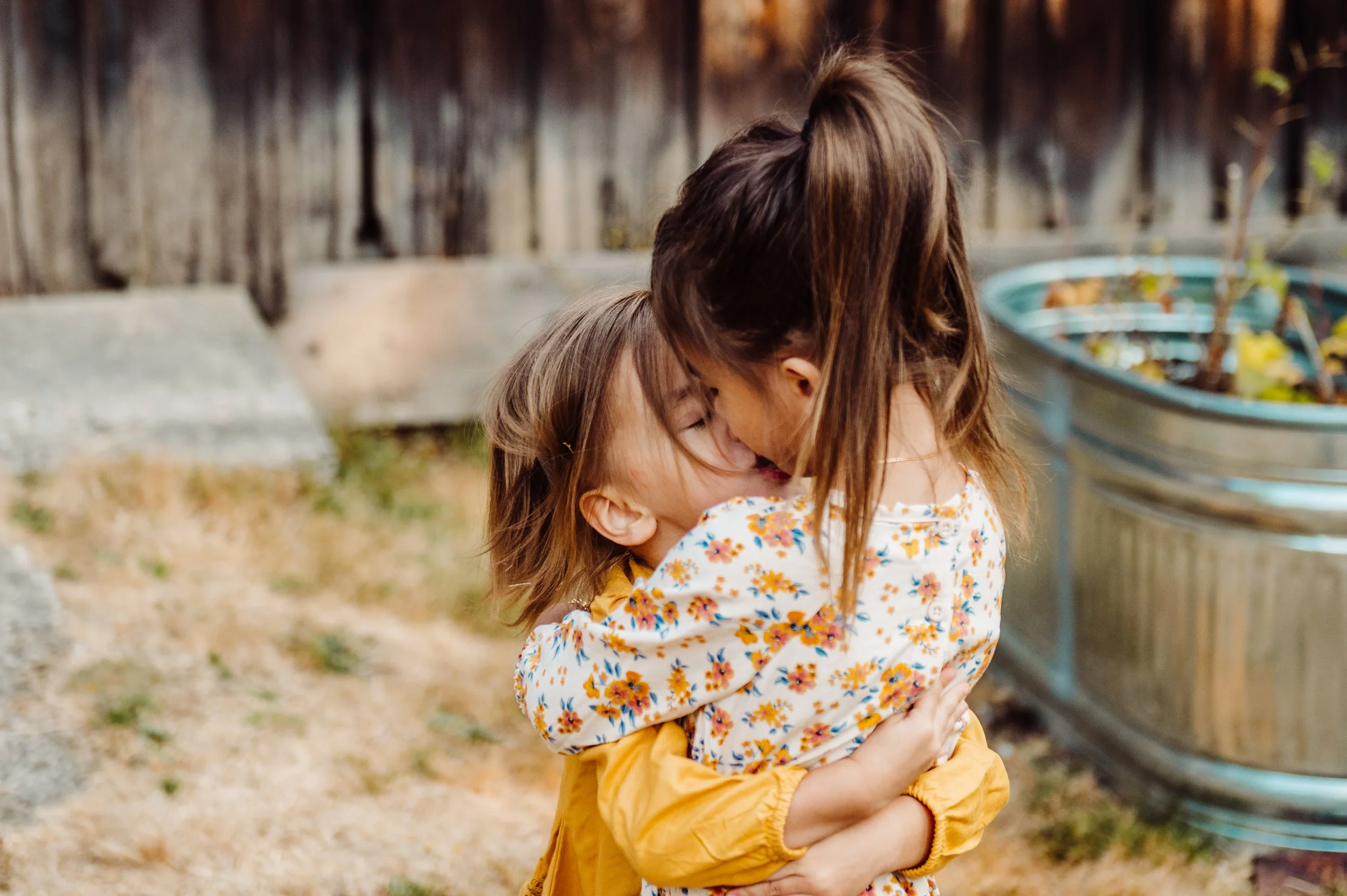 Two sisters hugging at a family photography session in Kirkland par during the fall.