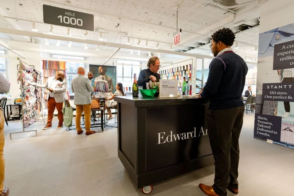A pop up bar with name Edward Armah and socializing around, and a display table with various items.