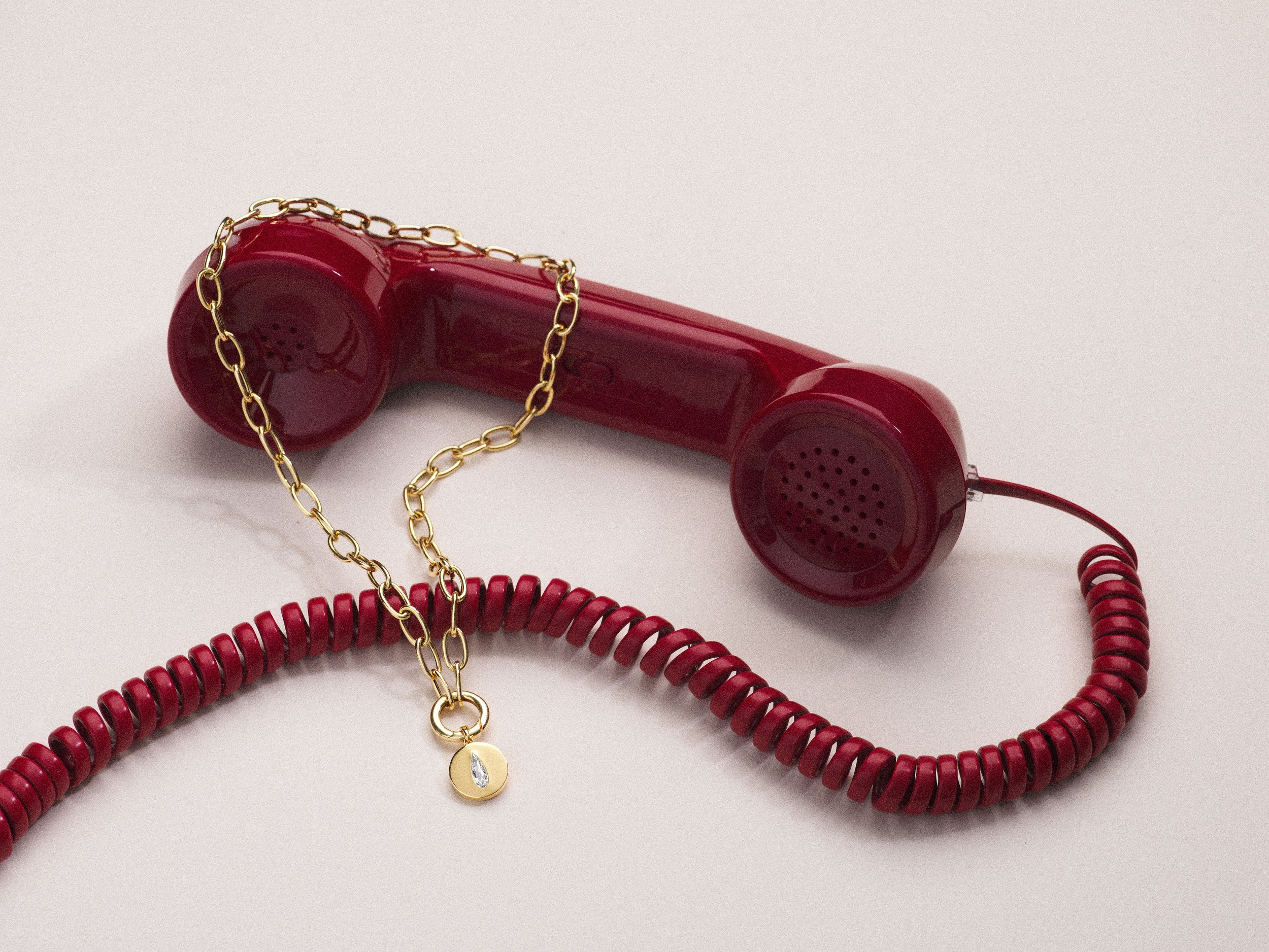 TOIL jewelry on vintage red telephone — editorial product photography by Little Wolf Collective