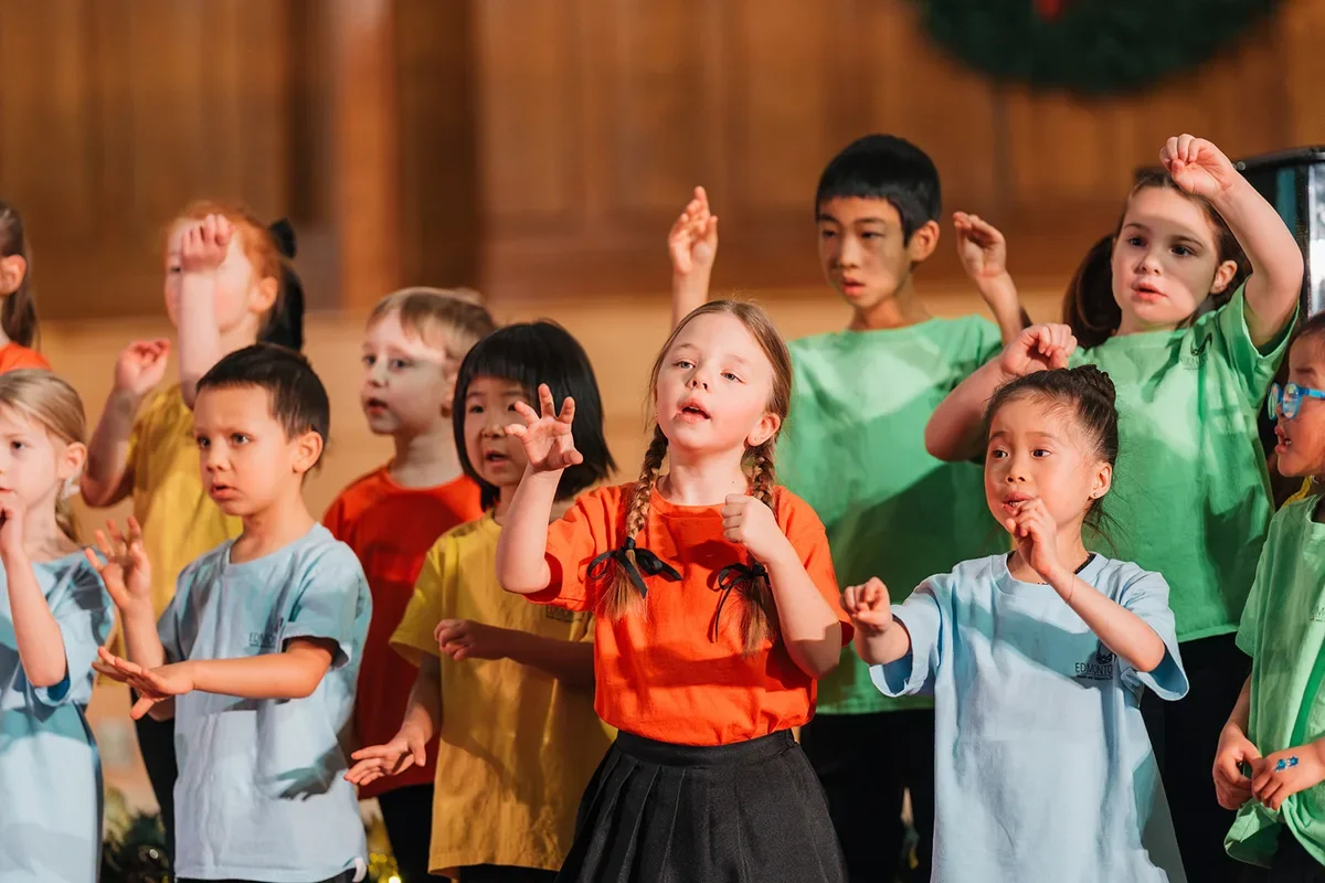 Young singers in bright T-shirts sing with hand actions, keeping the beat together