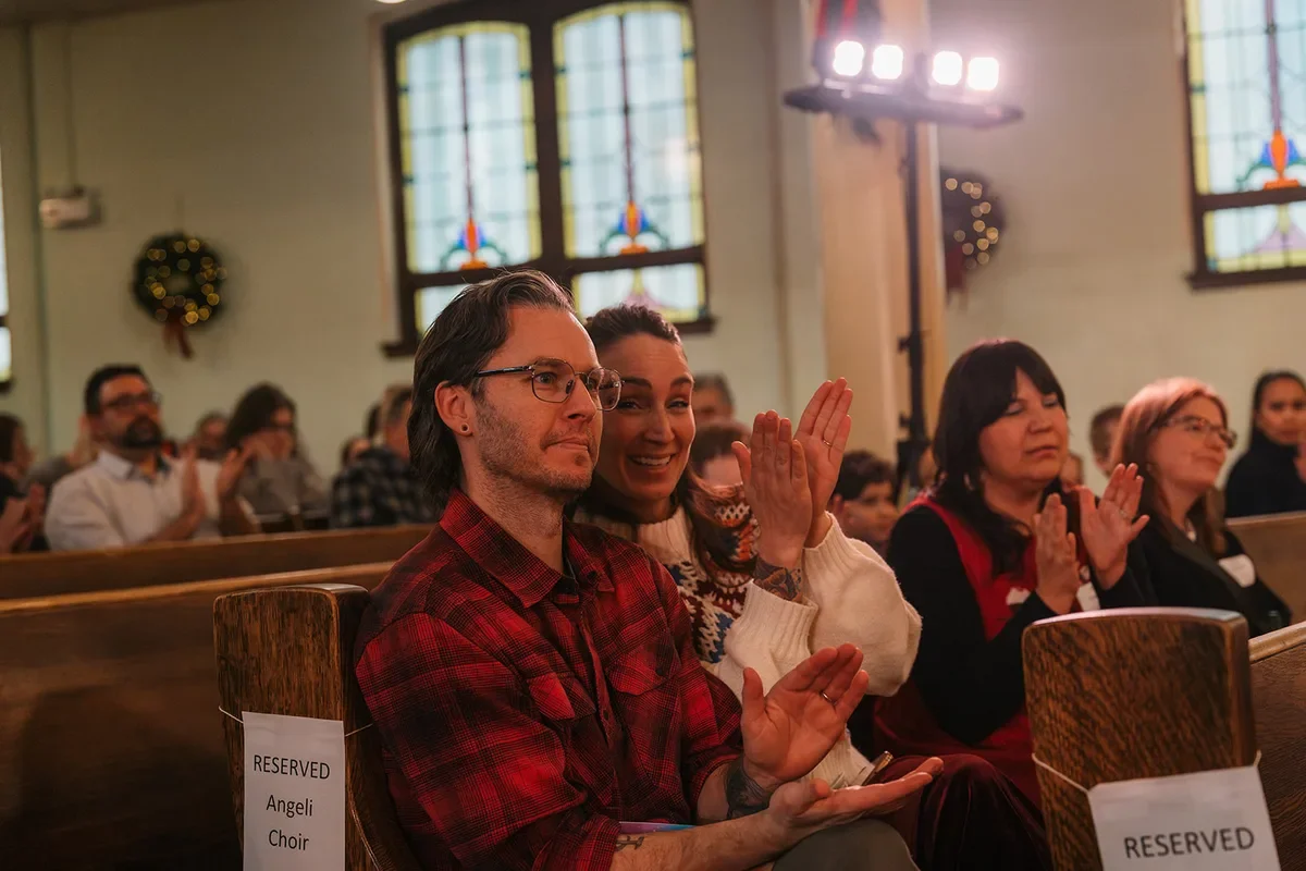 Parents in pews reserved for the Angeli Choir applaud their kids' after-school choir at a holiday concert