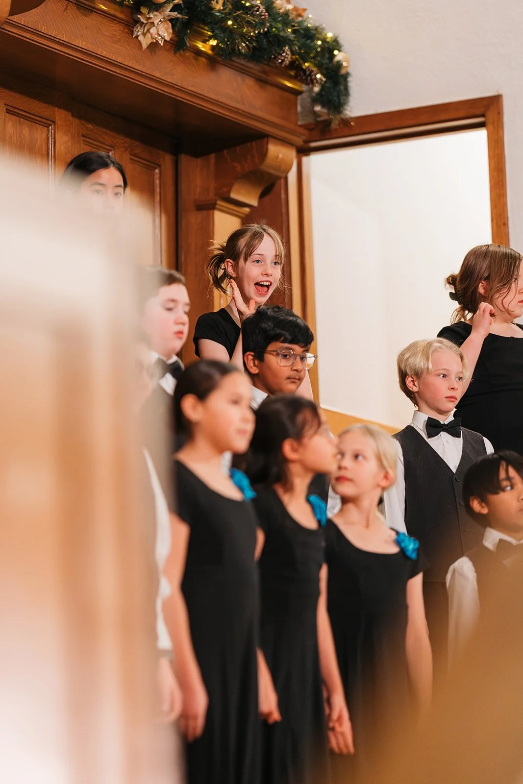 edmonton children's choir singer waving from the stage to her family in the audience