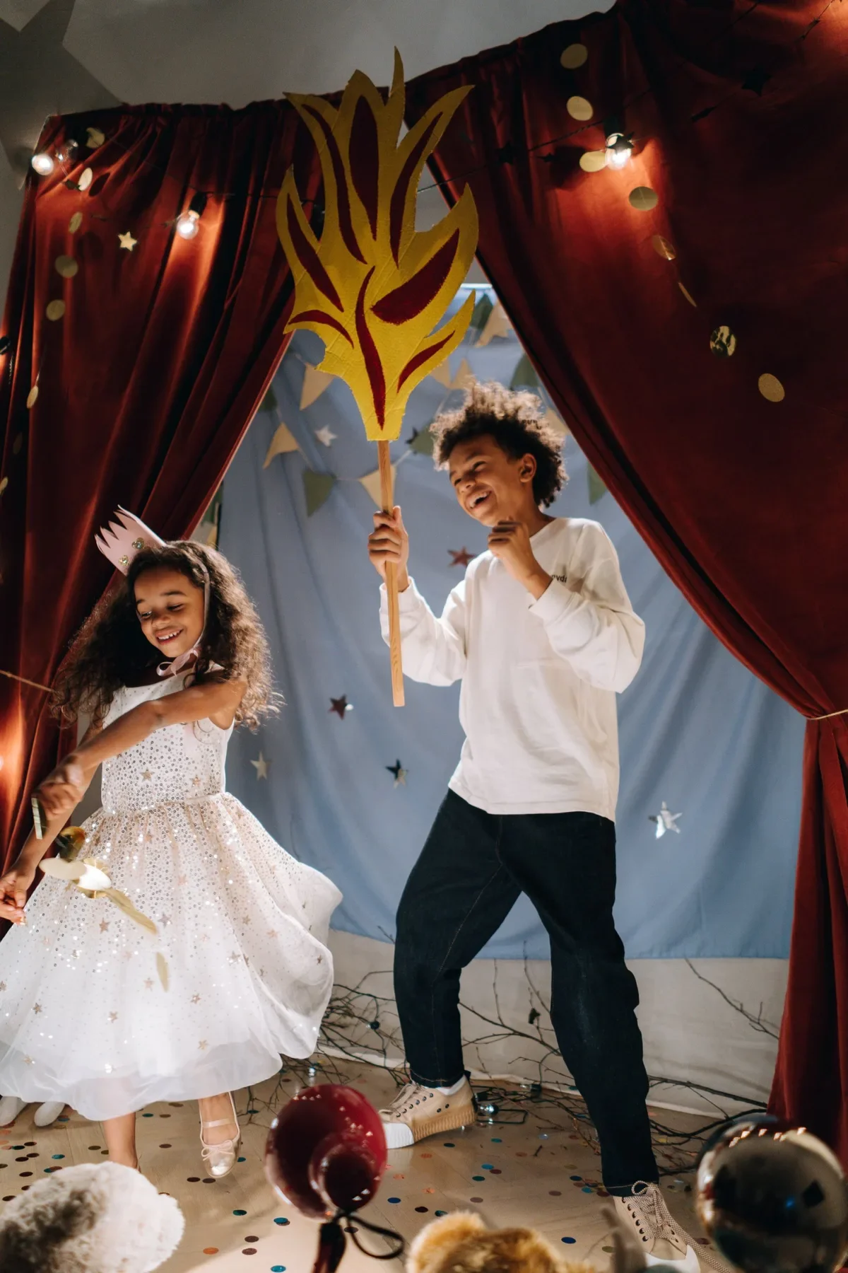 Two costumed kids dance on a homemade stage, a taste of after-school activities like drama and pretend play
