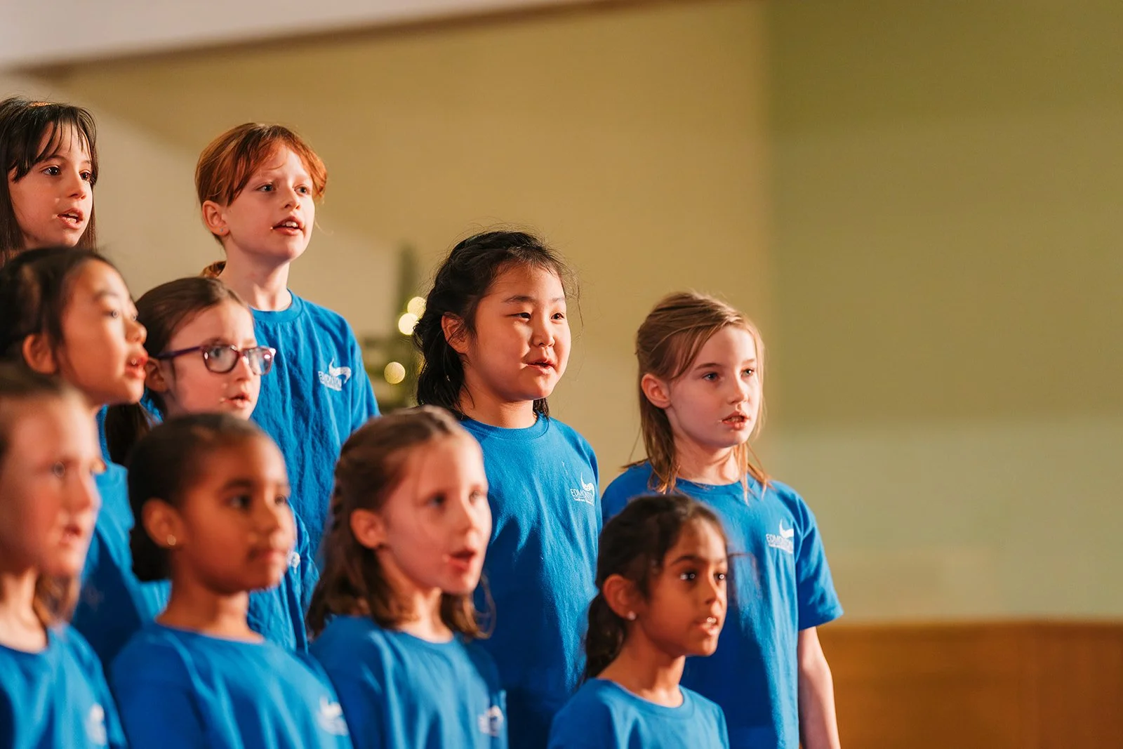 a choir for kids performing at a christmas concert wearing royal blue shirts