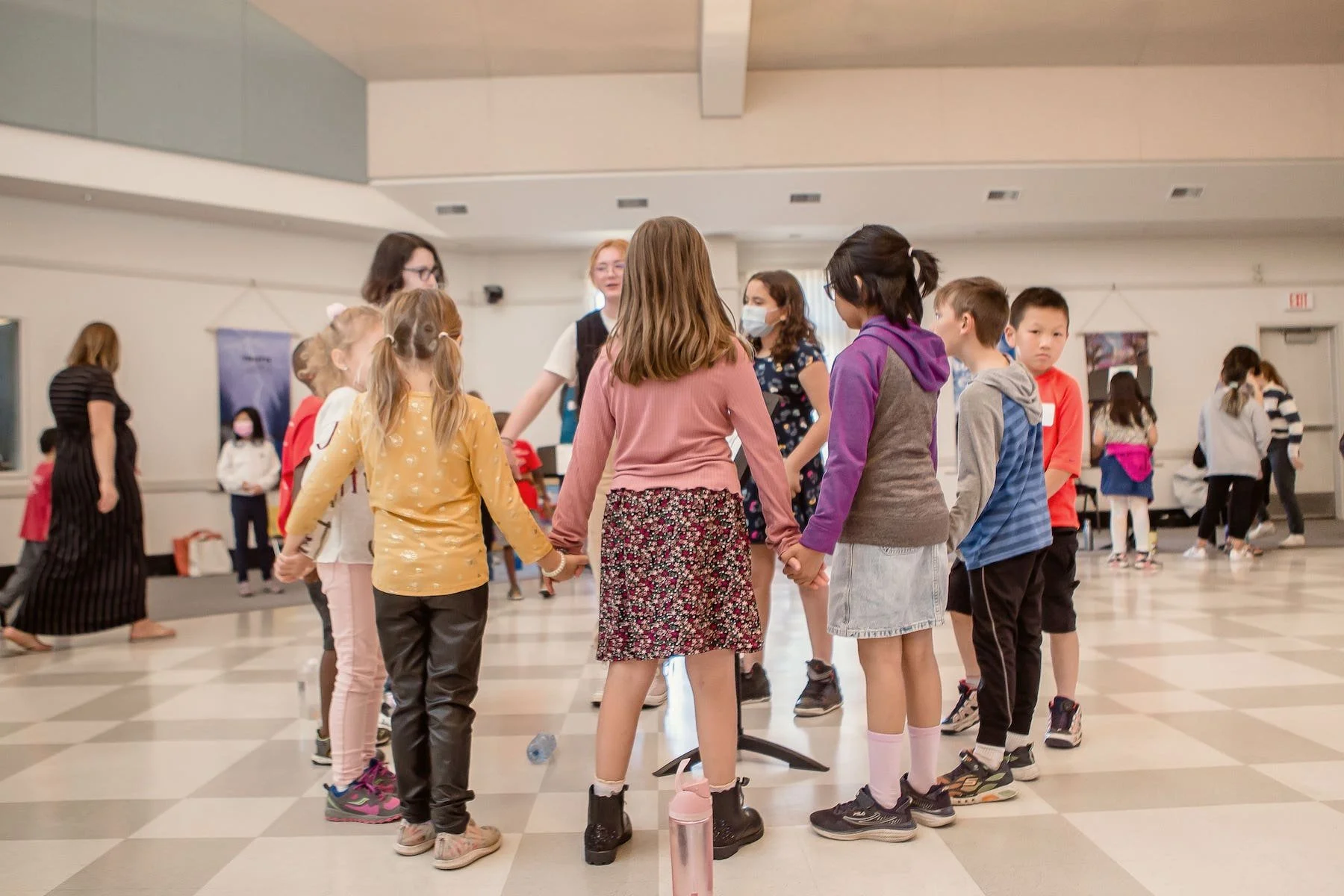 kids at an edmonton summer music camp holding hands and standing in a circle playing a music game