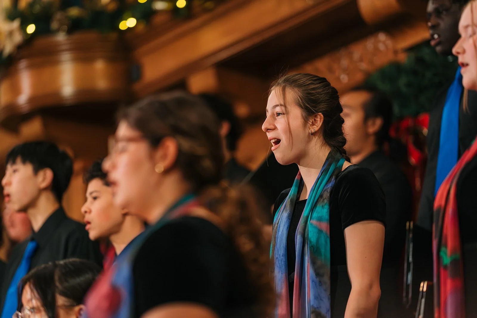 Edmonton youth choir singer performing on stage at the christmas concert wearing a black dress and colourful scarf