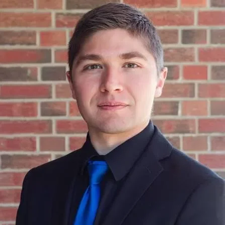 Josiah Maxfield, assistant conductor of Resound choir in Edmonton, in a black suit and blue tie