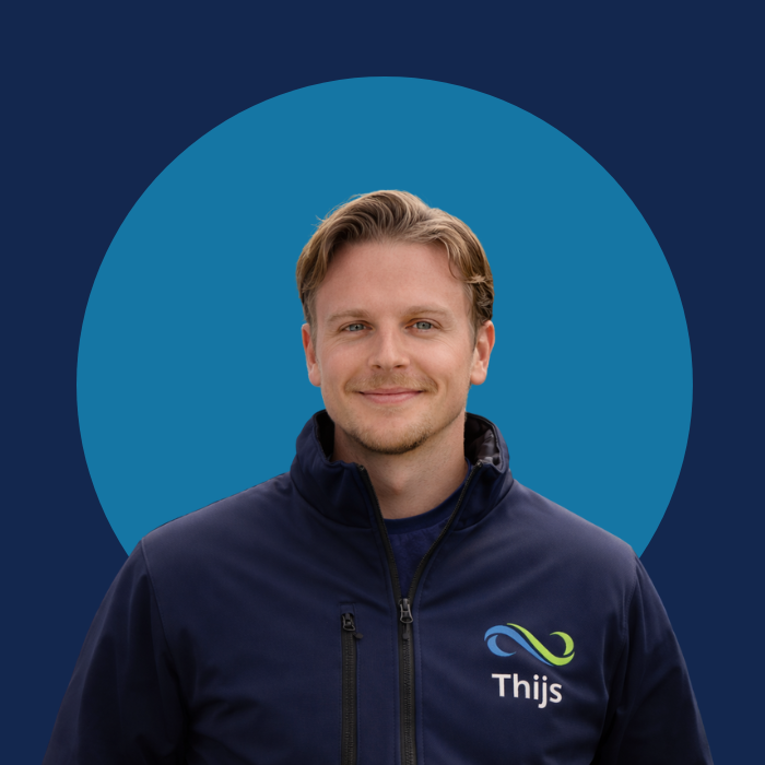Man met blond haar, blauwe jas met logo en tekst 'Thijs', glimlach, voor een blauwe achtergrond met een groter blauwe cirkel erachter.
