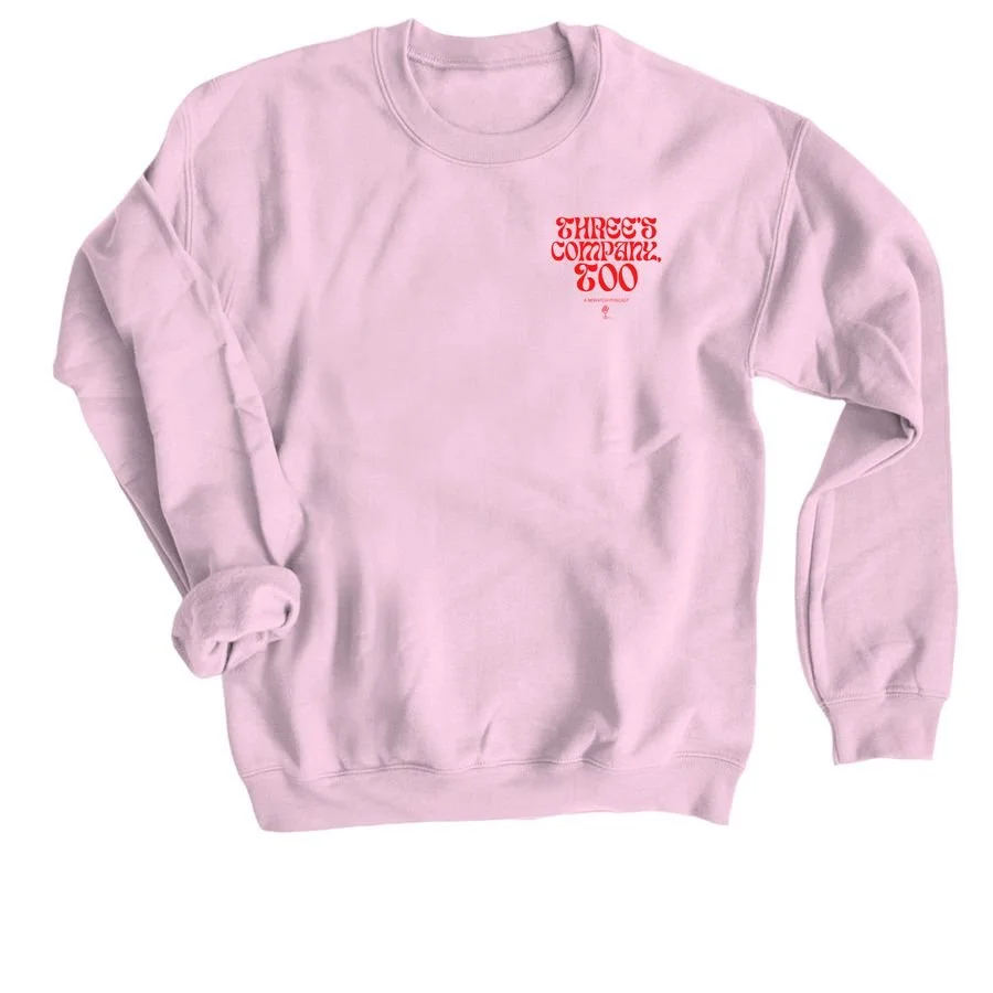 Pink sweatshirt with red text reading 'Three's Company, Too' on the upper left side.