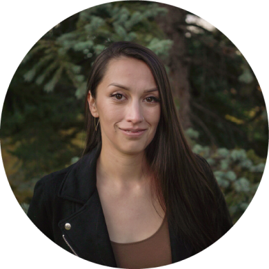 A smiling person infront of a blurred background of a tree