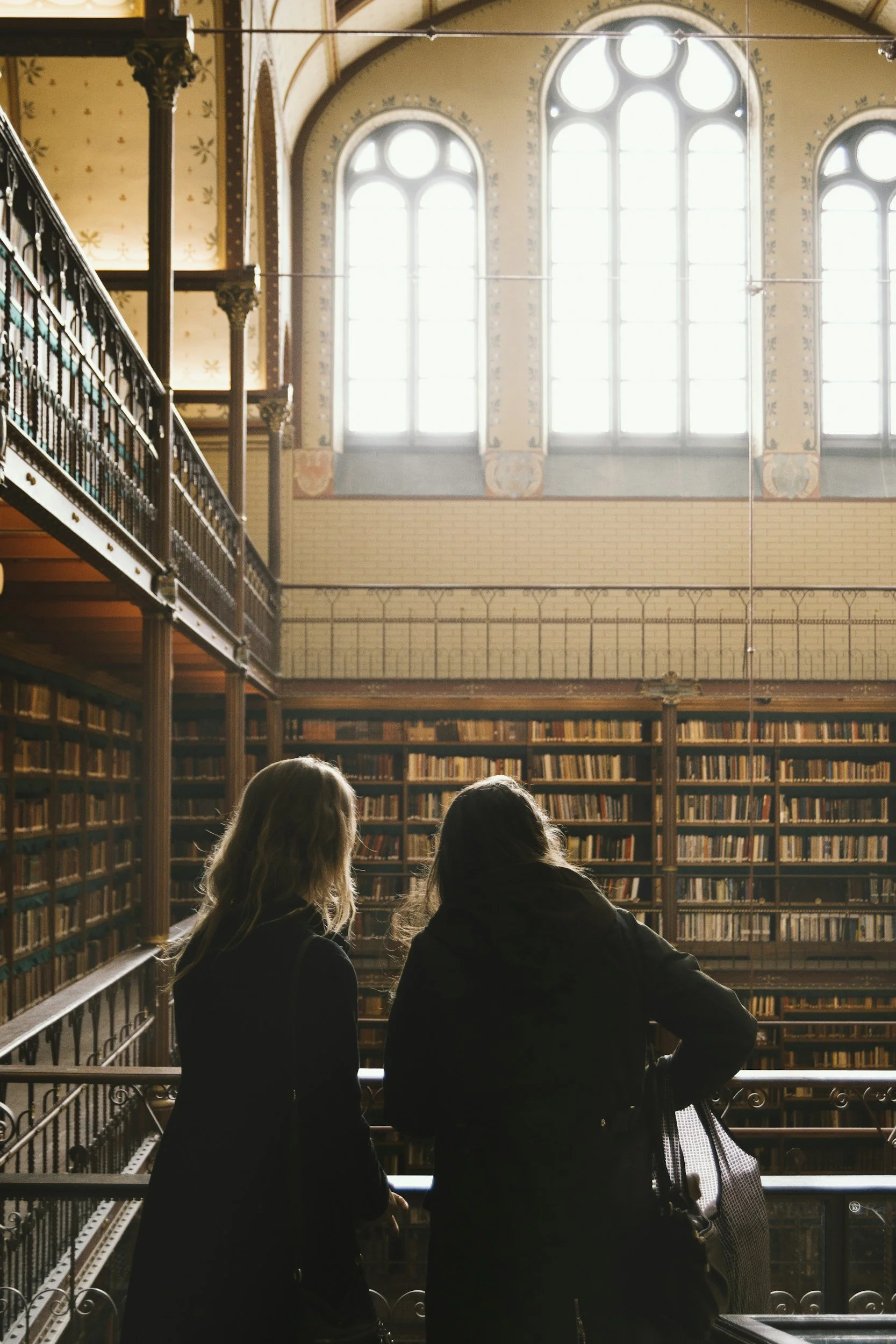 Two people stand in a grand, dimly lit library