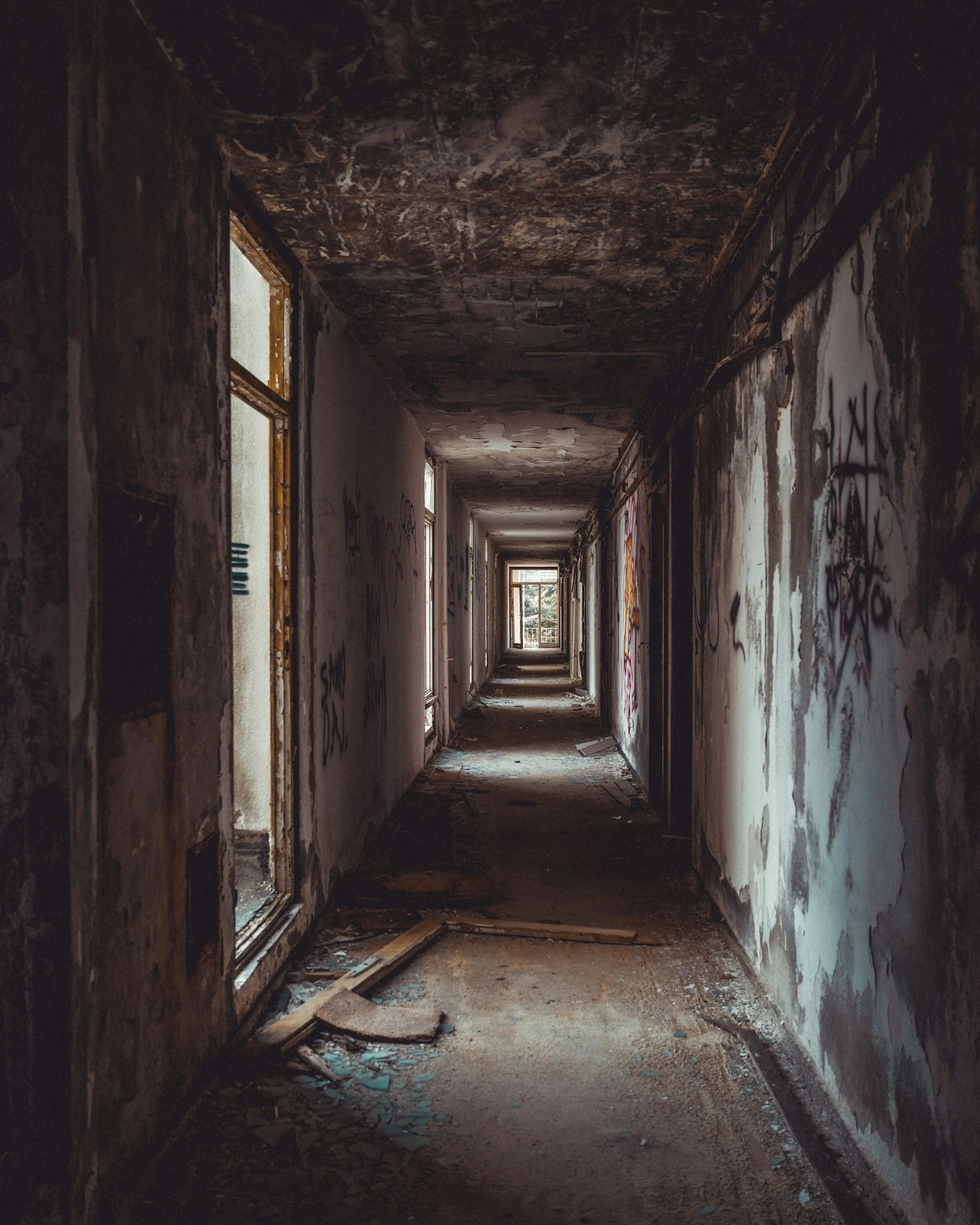 A long perspective shot of a decaying, abandoned hallway with peeling paint, styled as a dark ambient author website background image