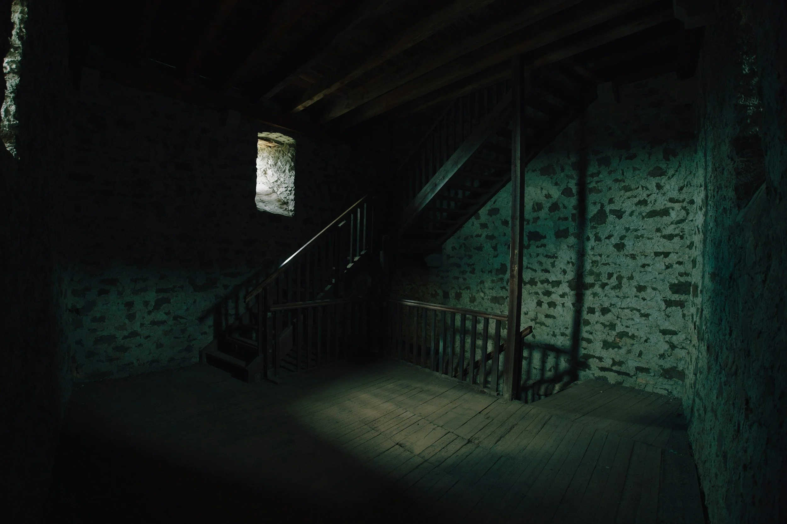 A cavernous stone room with a staircase, highlighting visual branding styles for a gothic novelist website