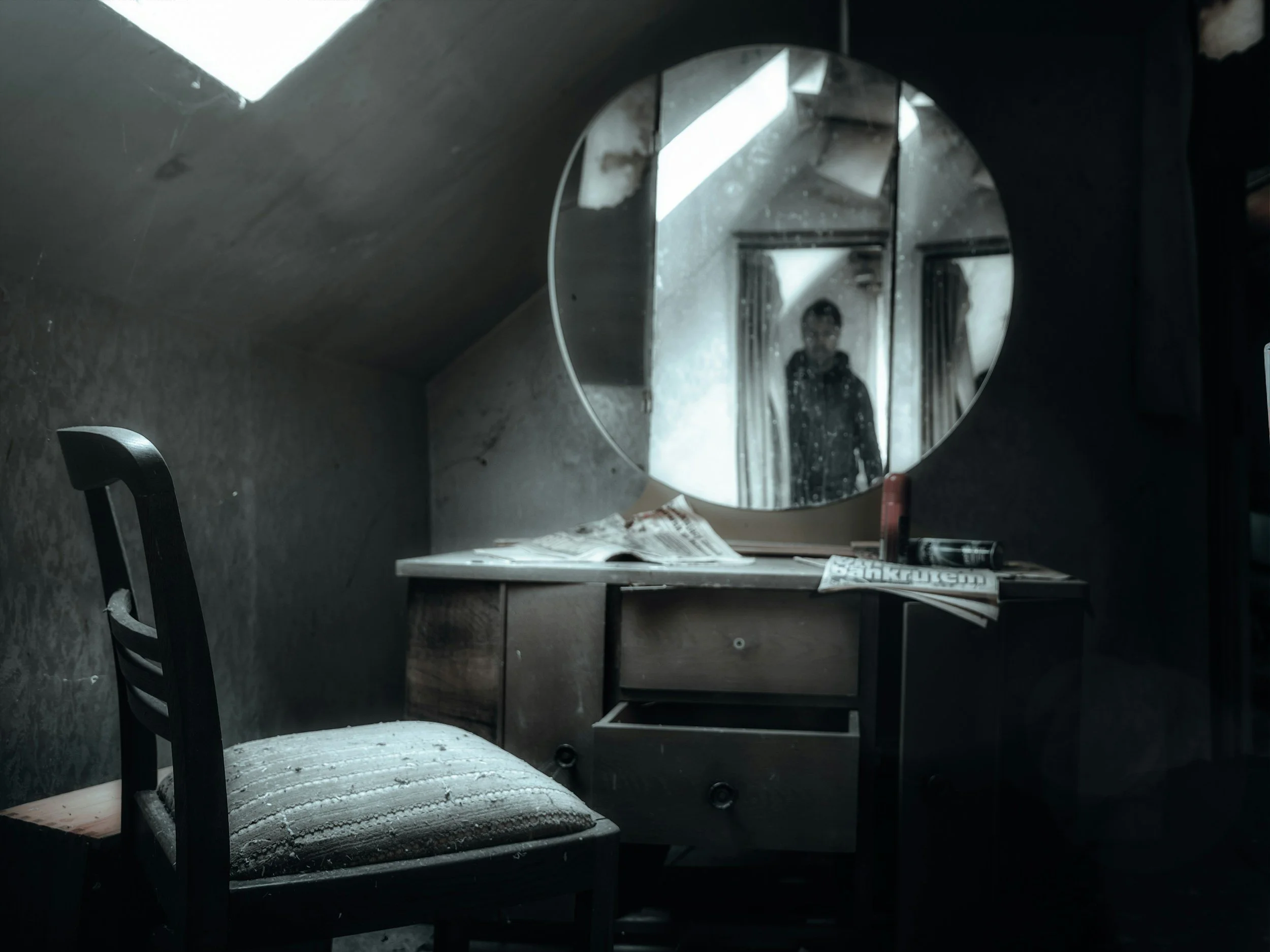 A dim, dusty bedroom vanity mirror showing a dark silhouette reflection, representing a haunted aesthetic for horror author branding