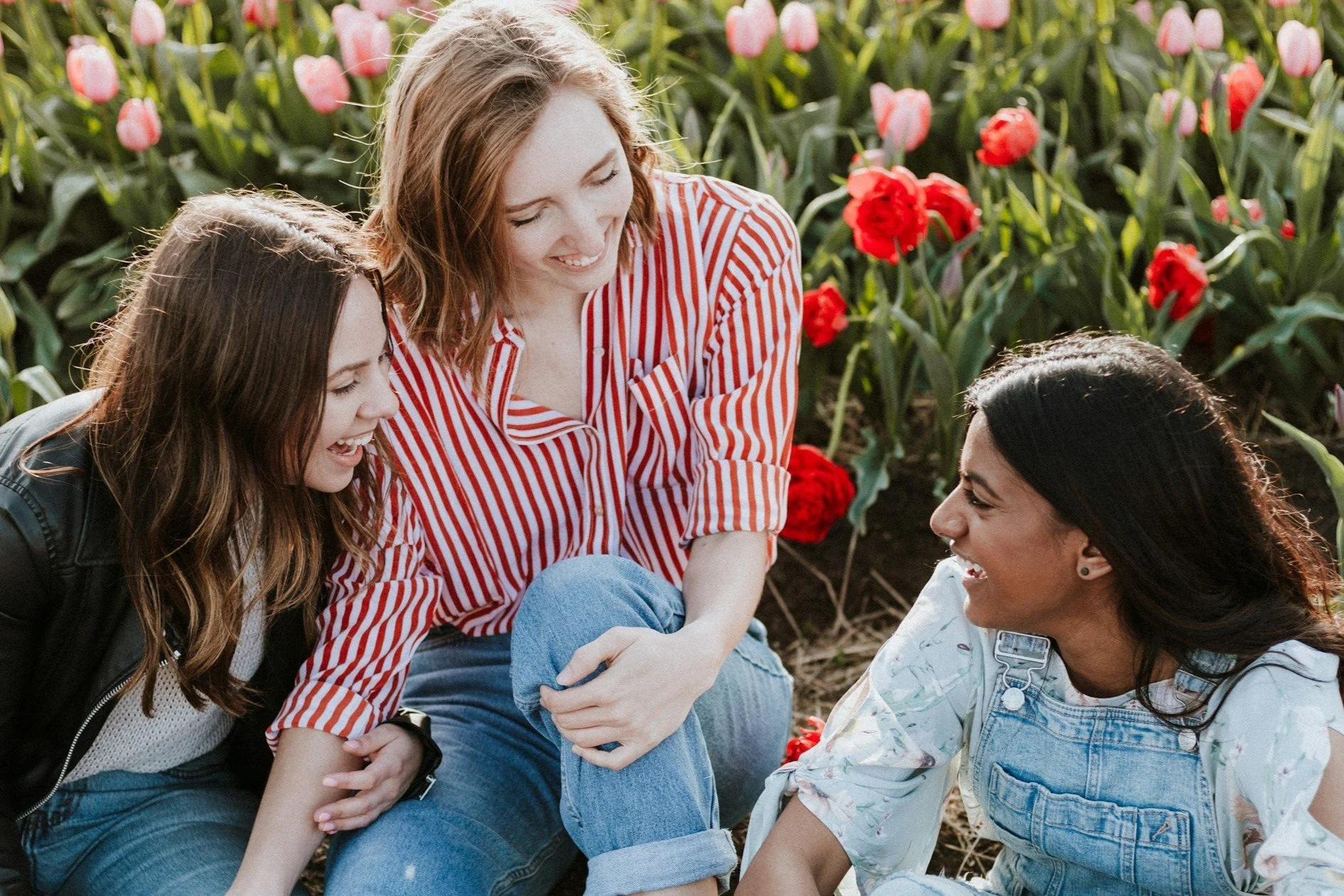 Two young women laughing in a tulip field, illustrating the confidence and improved self-esteem found through teen counseling at Everthrive Counseling in New Port Richey.