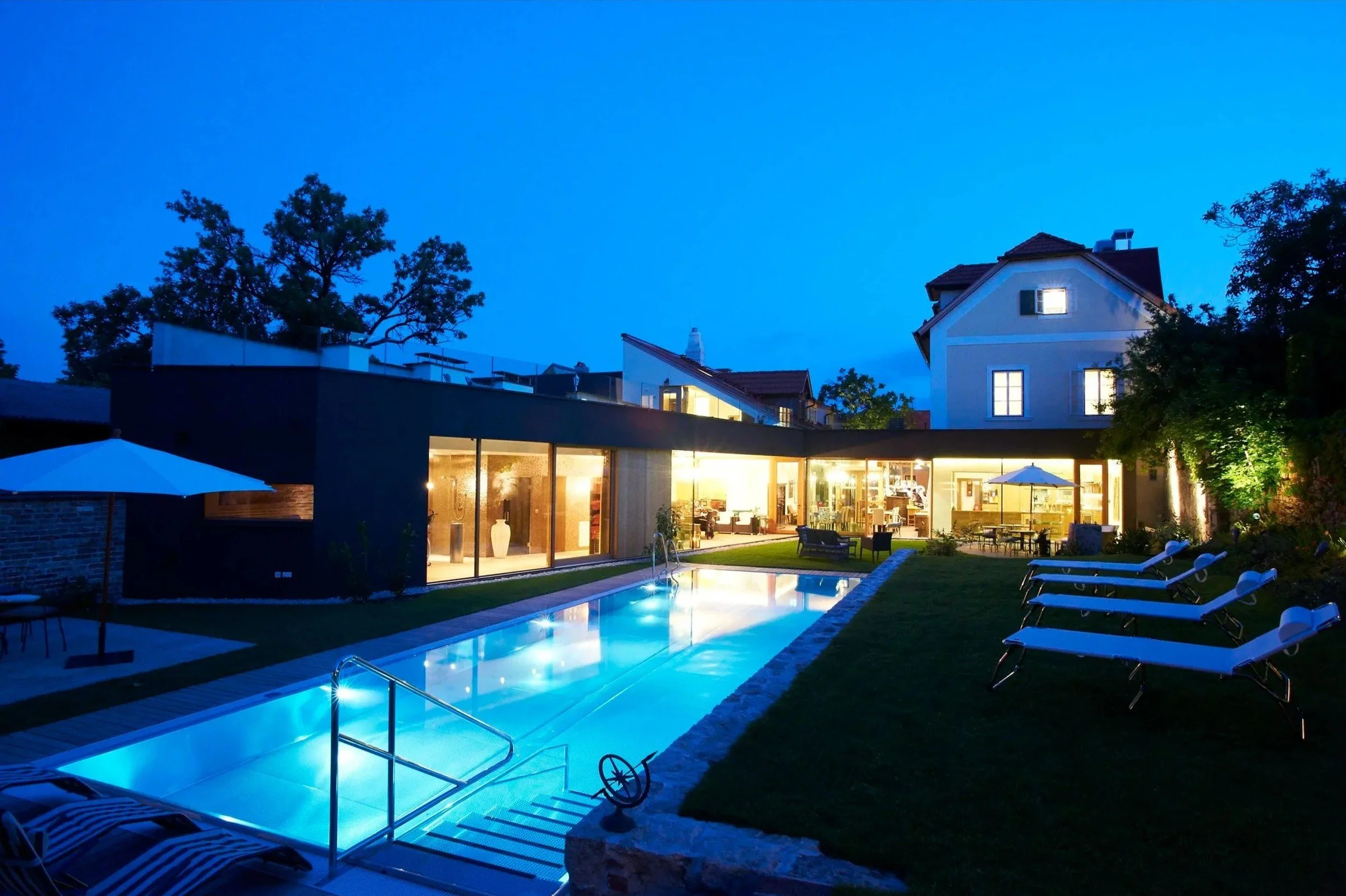 Die Gartenansicht des Hotel Landhaus Moserhof in Gumpoldskirchenmit Außenpool im NIRO-Design lädt zum Schwimmen ein. Die Abendstimmung verführt zu einem Glaserl Wein.