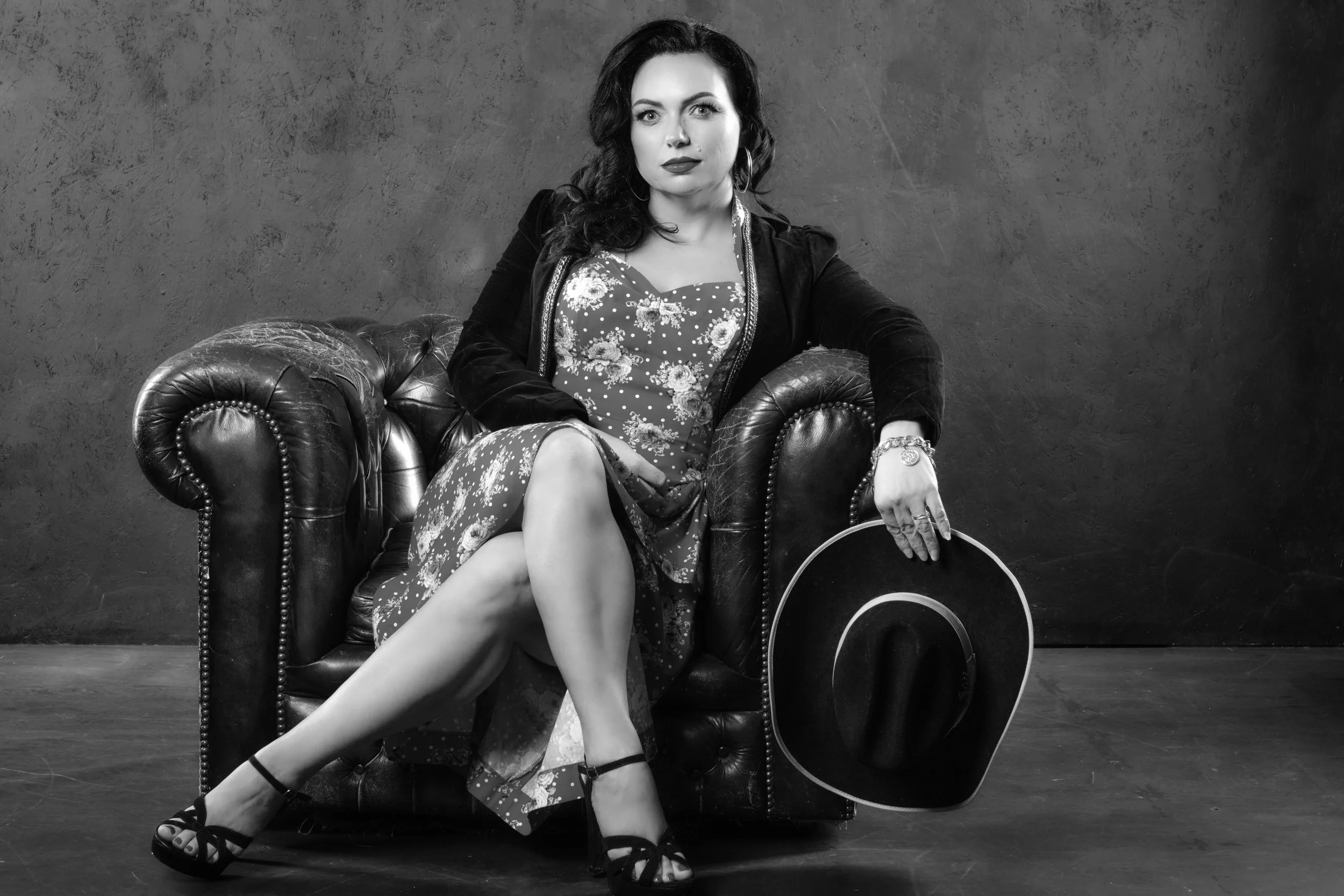 Dani West captured in a vintage-inspired studio portrait for Wild Records, seated in a leather armchair with classic styling that reflects timeless rockabilly and Americana influences