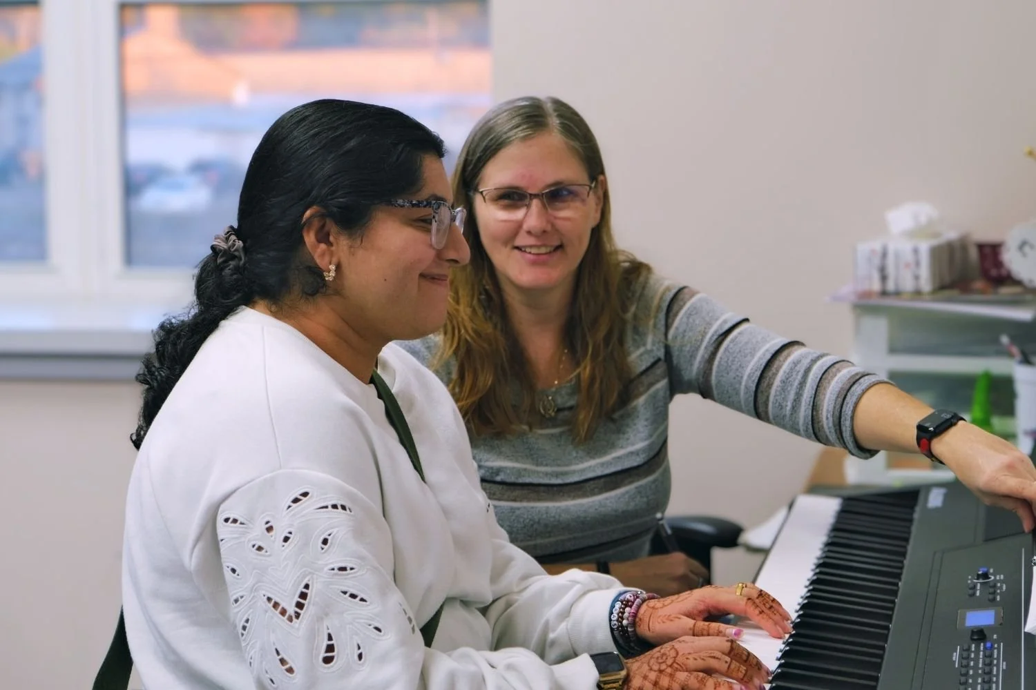 A Yellow Brick Music instructor guiding an adult during a piano lesson