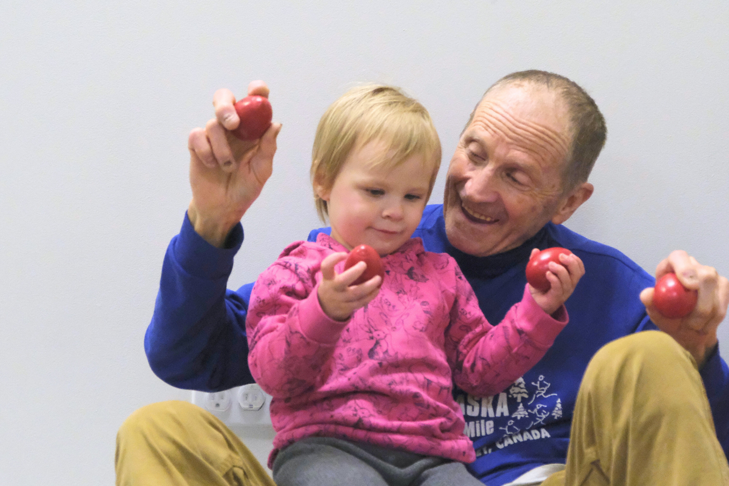 Child and grandparent practice rhythm and movement along to music with shakers