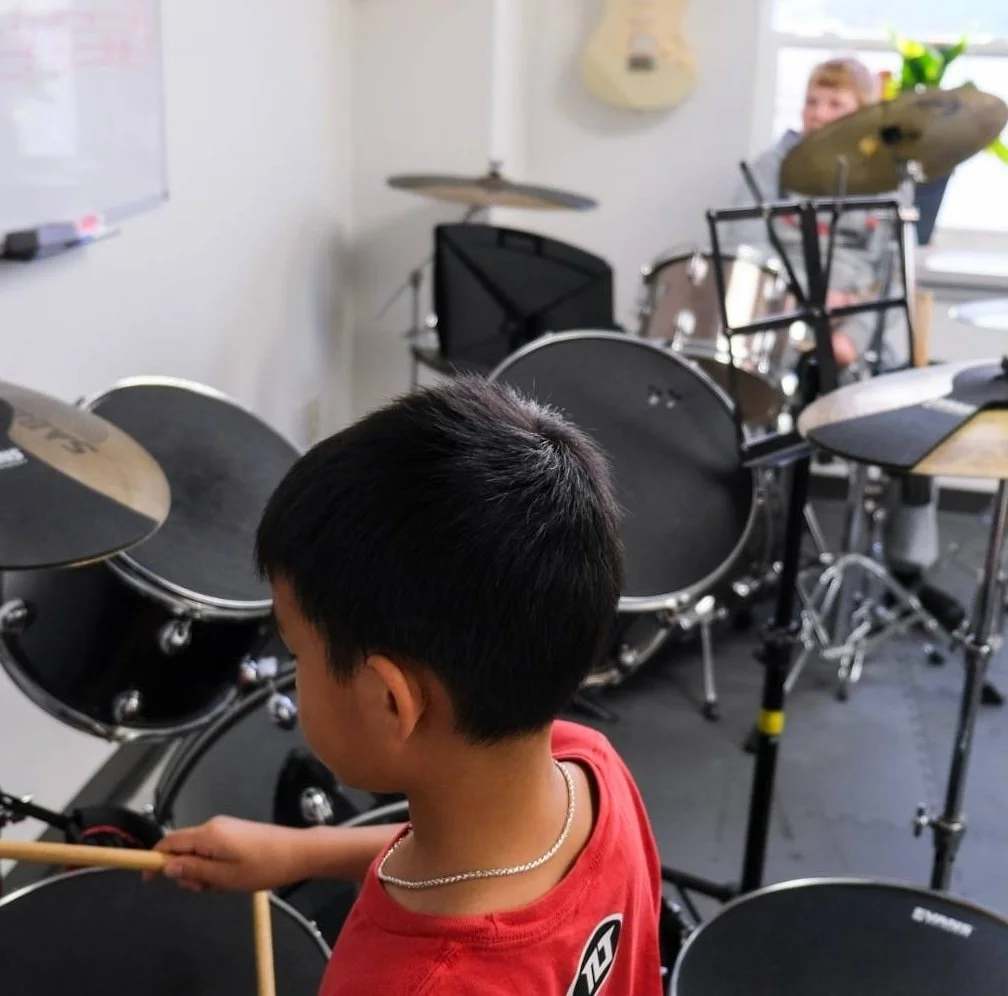 Kids playing a song in a group children's beginner drum class in a Hespeler music studio