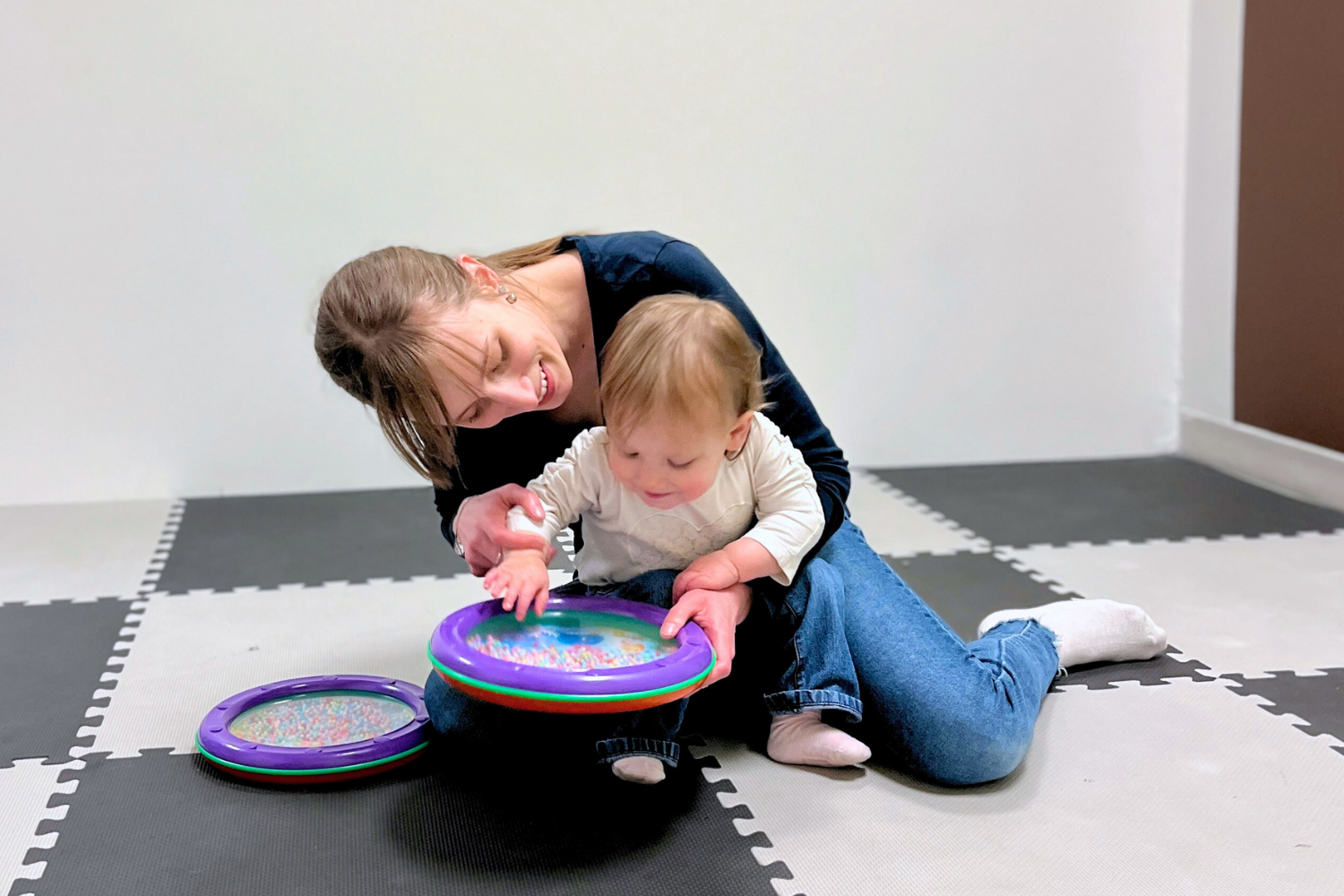 A toddler and their parent learning patterns with a toy drum