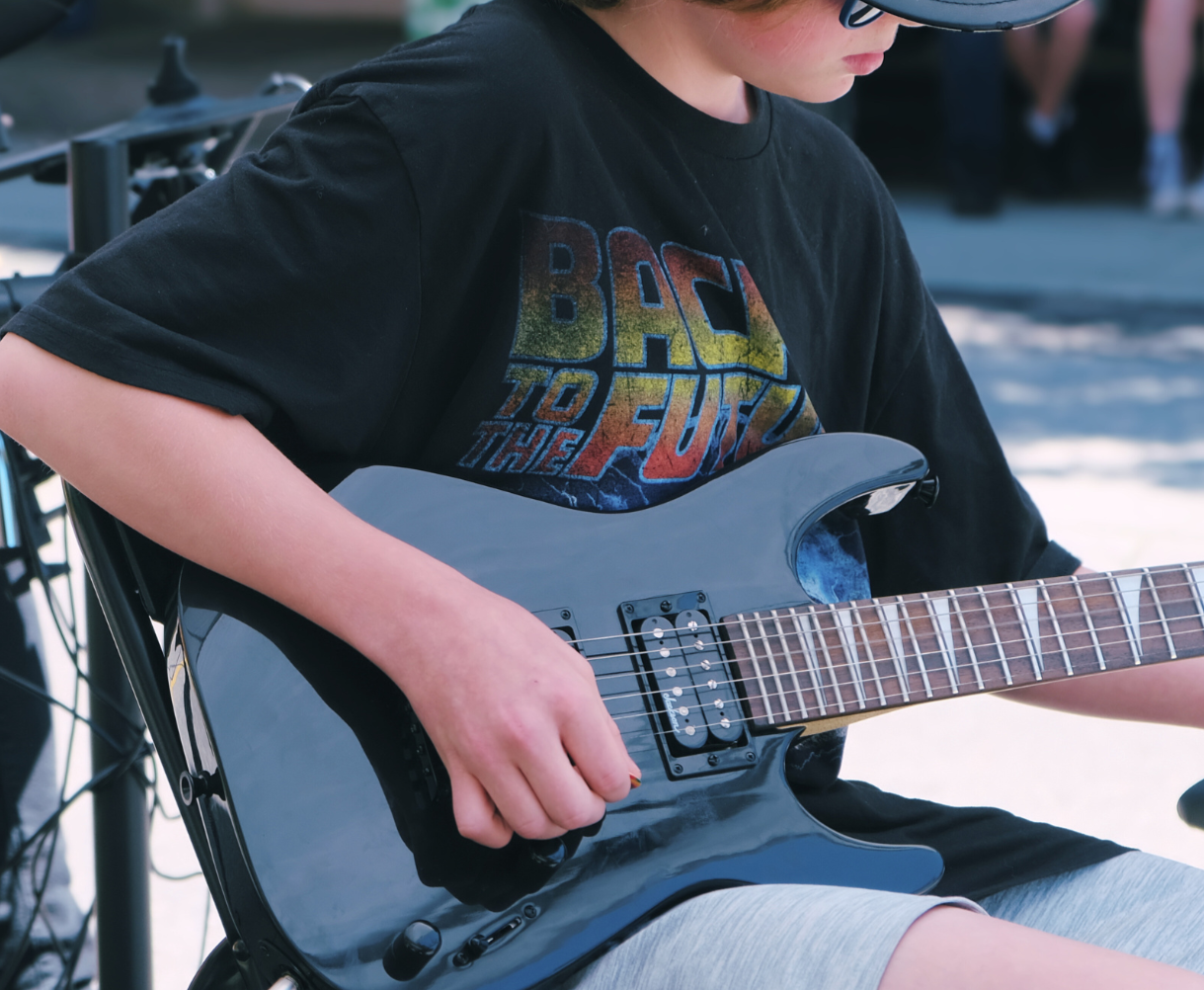 Close-up of a school-aged child playing electric guitar.