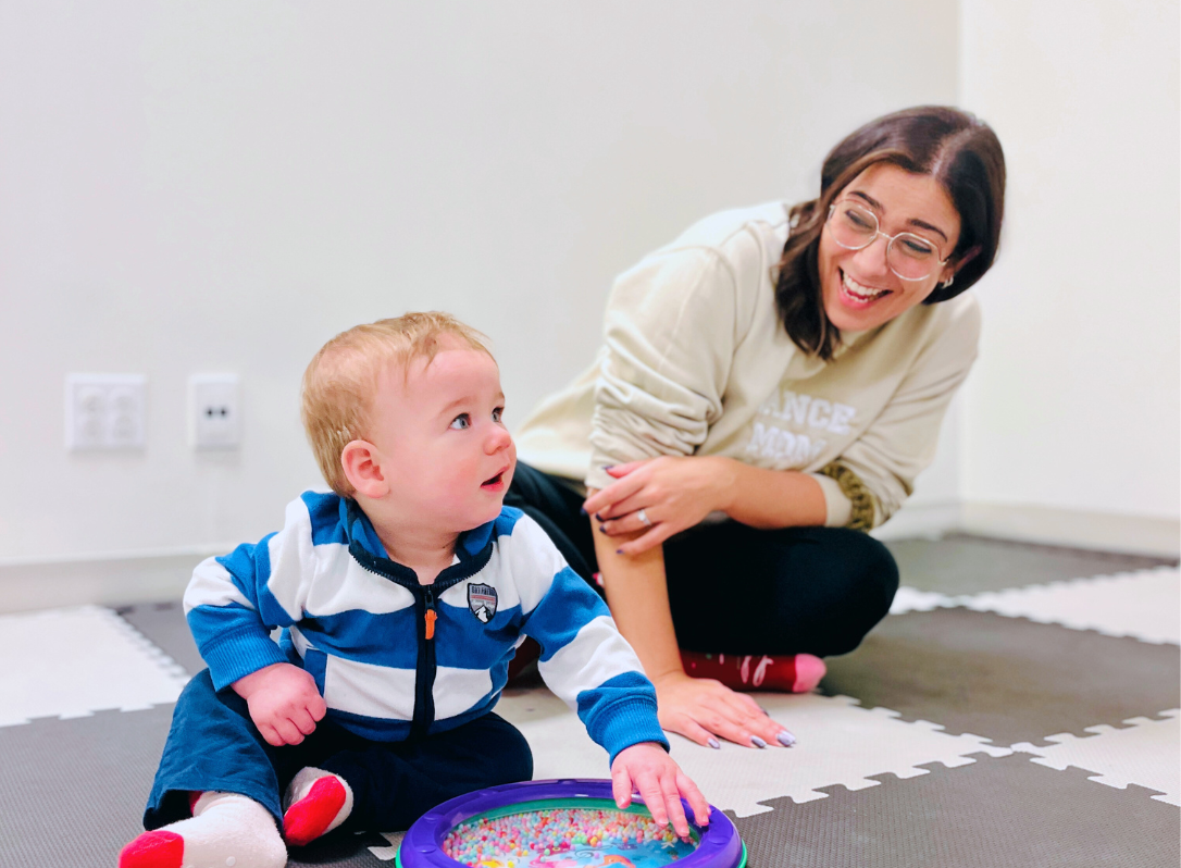 A young child exploring a drum during an Early Years Music class