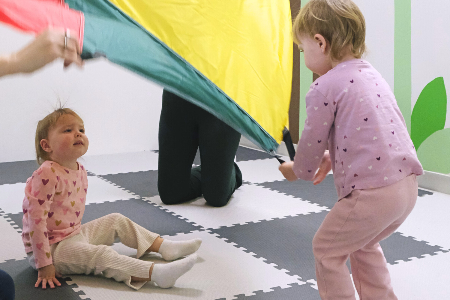 Children learning to share and take turns playing with a parachute in music class.