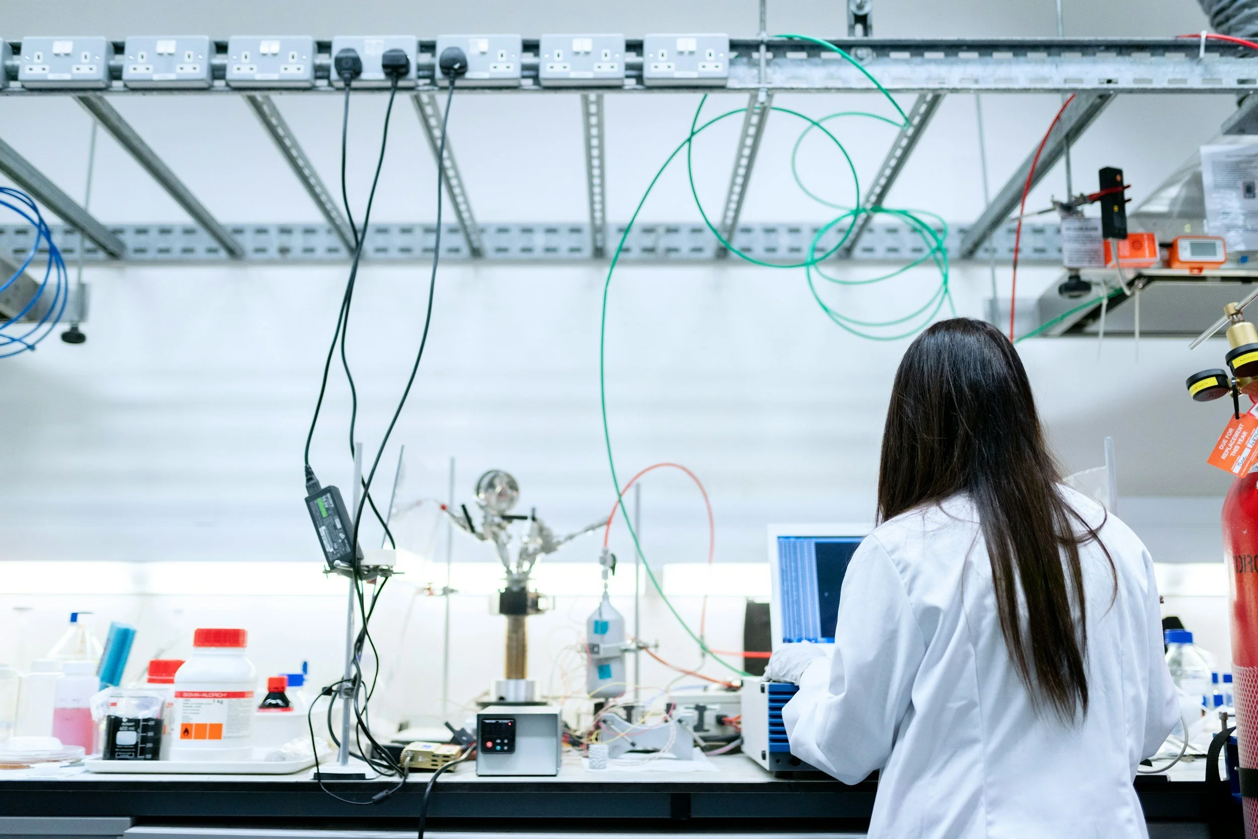 Scientist in lab coat working in a laboratory with equipment and cables, we make design labs for innovation