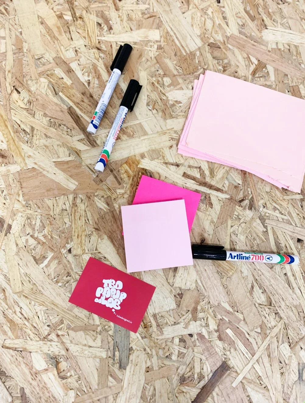 Markers and pink sticky notes on plywood surface. TBD pop up lab, design research for swedish welfare system of the future.