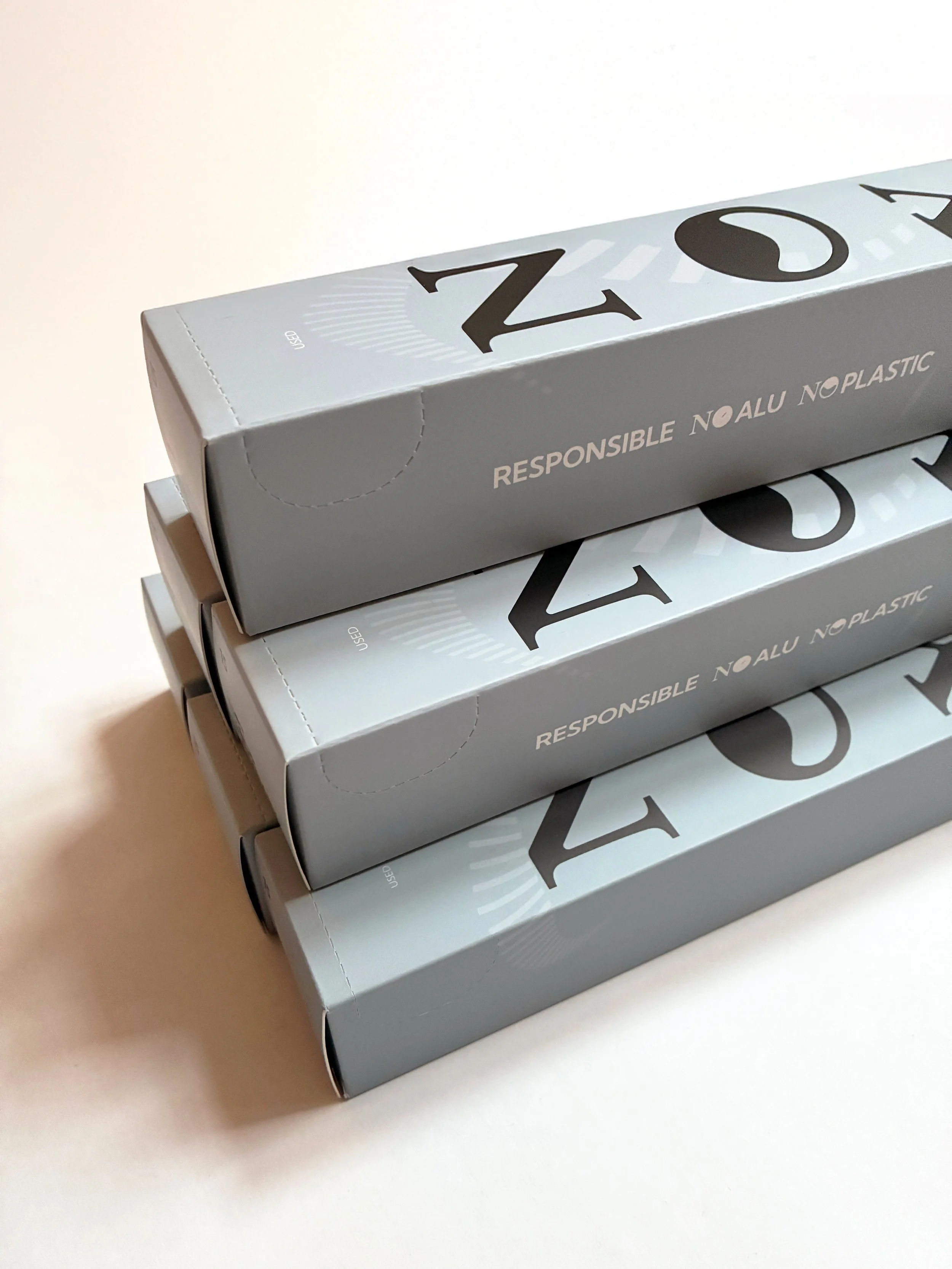 Three stacked boxes with gray and black packaging, labeled 'NOYO', and the text 'Responsibly No Aluminum No Plastic'. Designed by TBD Studios Stockholm Uppsala. To Be Designed.