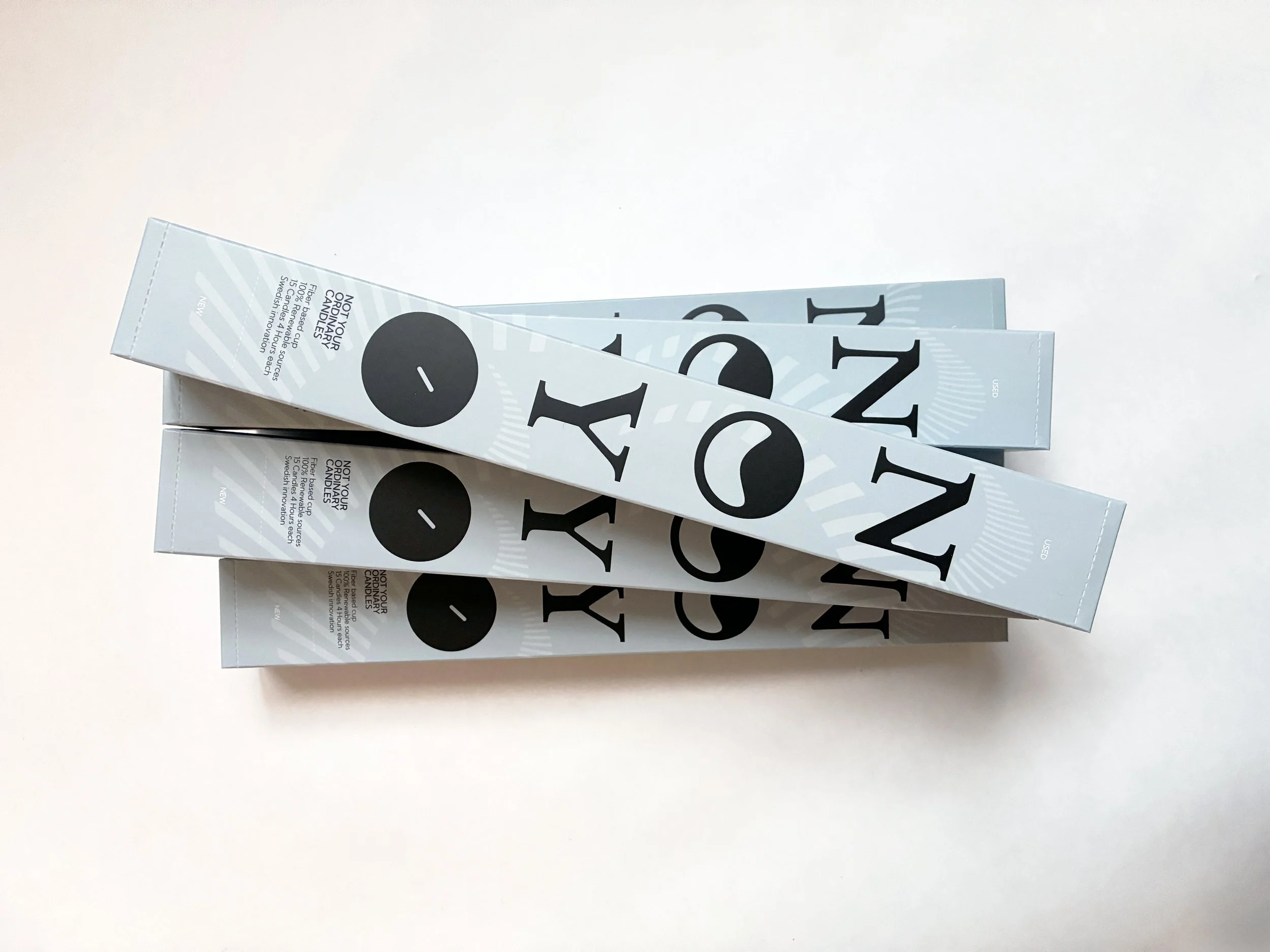 Three stacked boxes of NOYO Not Your Ordinary Candles product on white background. Designed by TBD Studios Stockholm Uppsala.