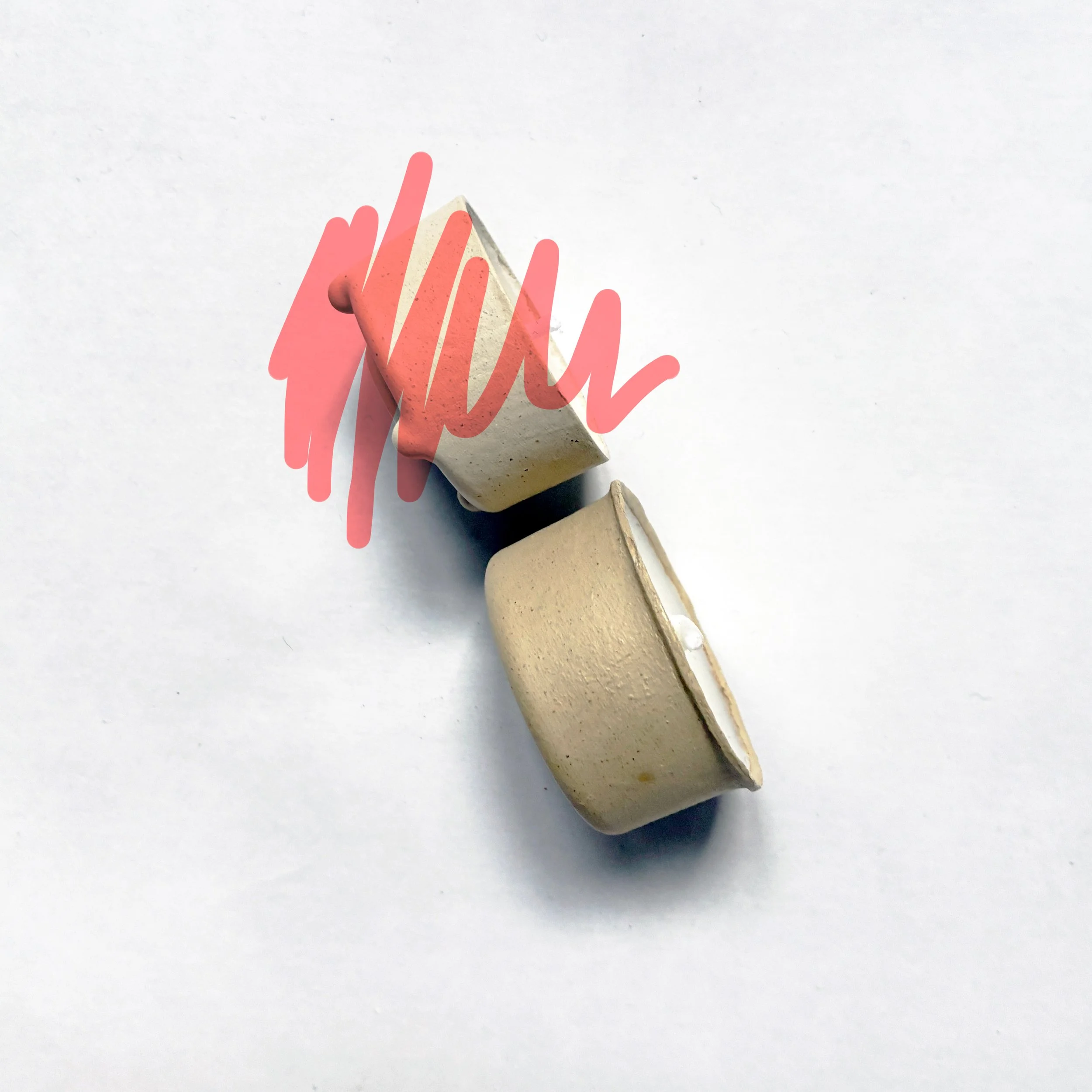 Two small fiber based candle prototypes, one lying on its side and the other standing upright, with red scribbles overlaying part of the image. JORD Innovation, design suport by To Be Designed.