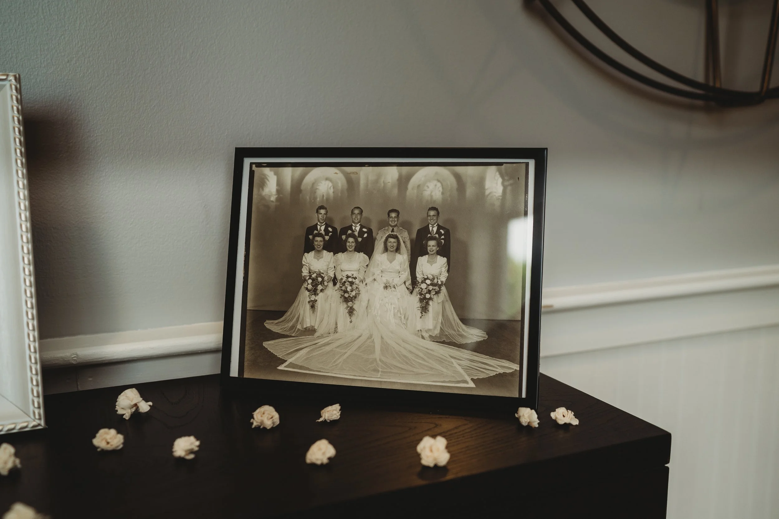 Black and white wedding photograph of a bride and groom with four bridesmaids and three groomsmen in a studio setting.