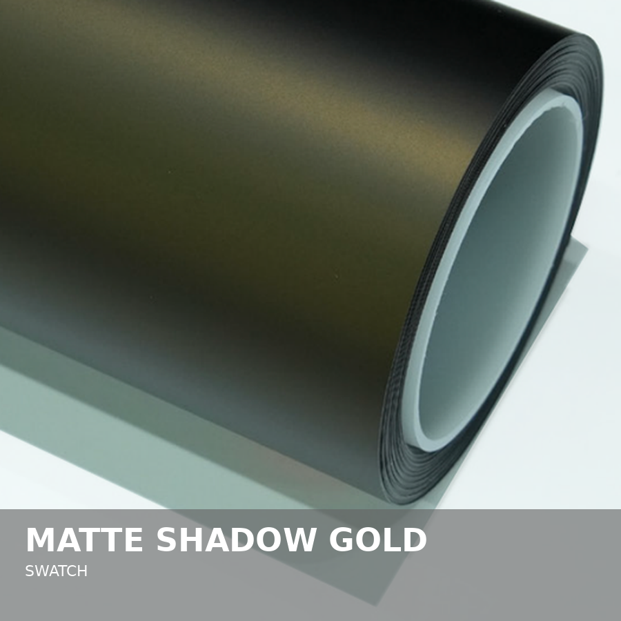 A roll of matte shadow gold heat transfer vinyl with a black backing side, resting on a white surface.