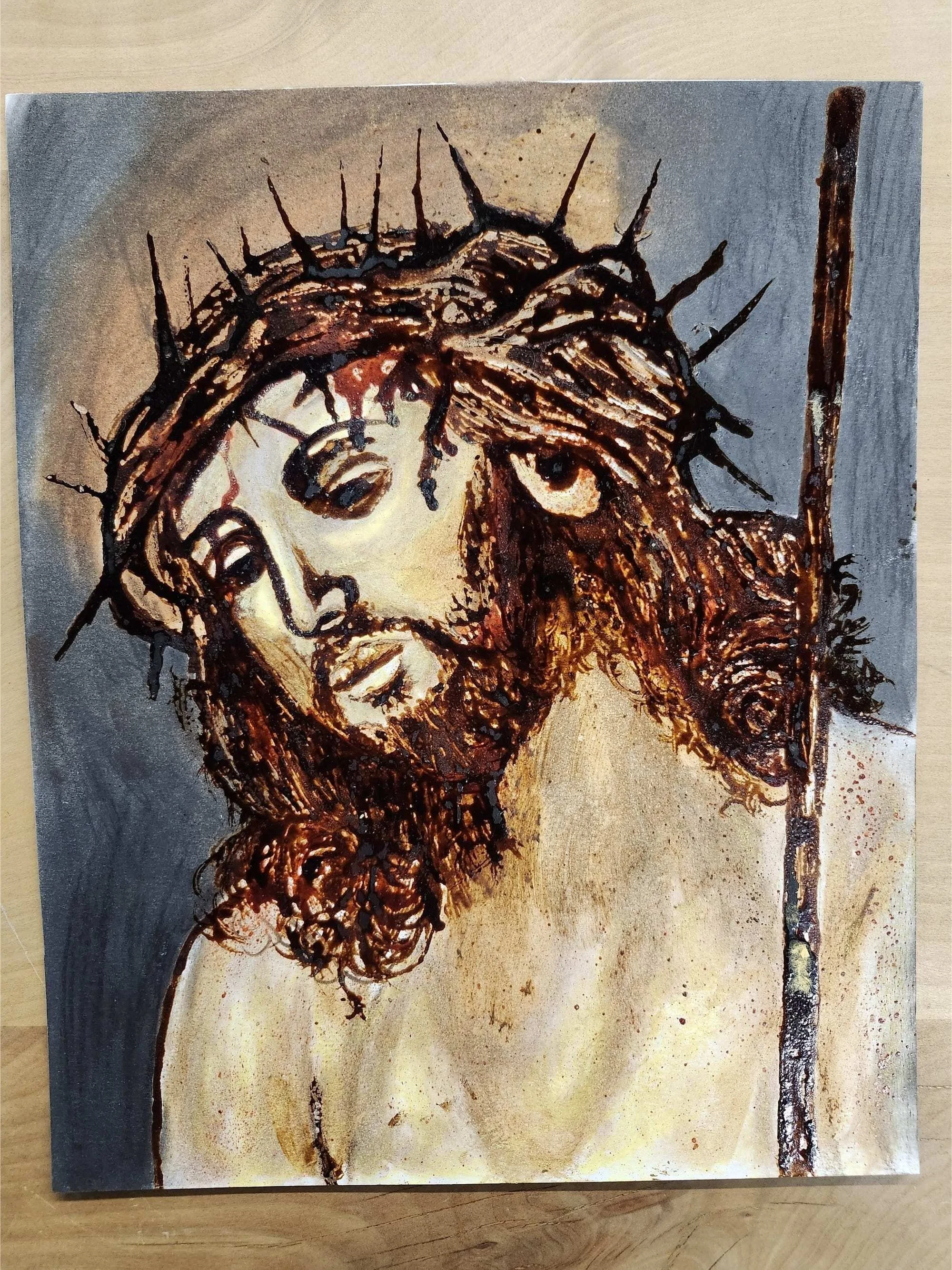 A colorful painting of Jesus wearing a crown of thorns. His face is downturned slightly, and he's bleeding from where the thorns have pierced his skin.