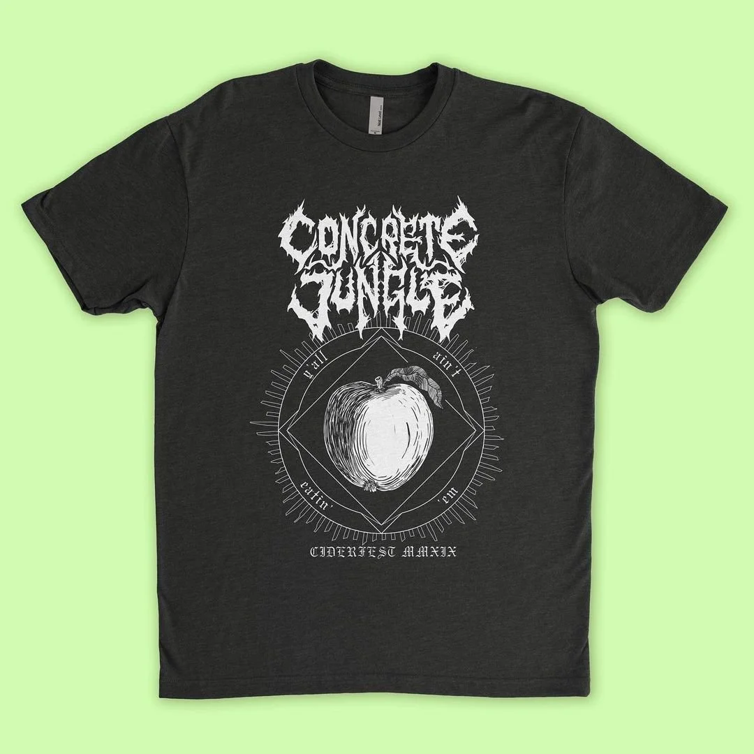 A black shirt with the text Concrete Jungle written in a style that's similar to a black metal logo. It features an apple in the middle with occult symbols and the text Cider fest