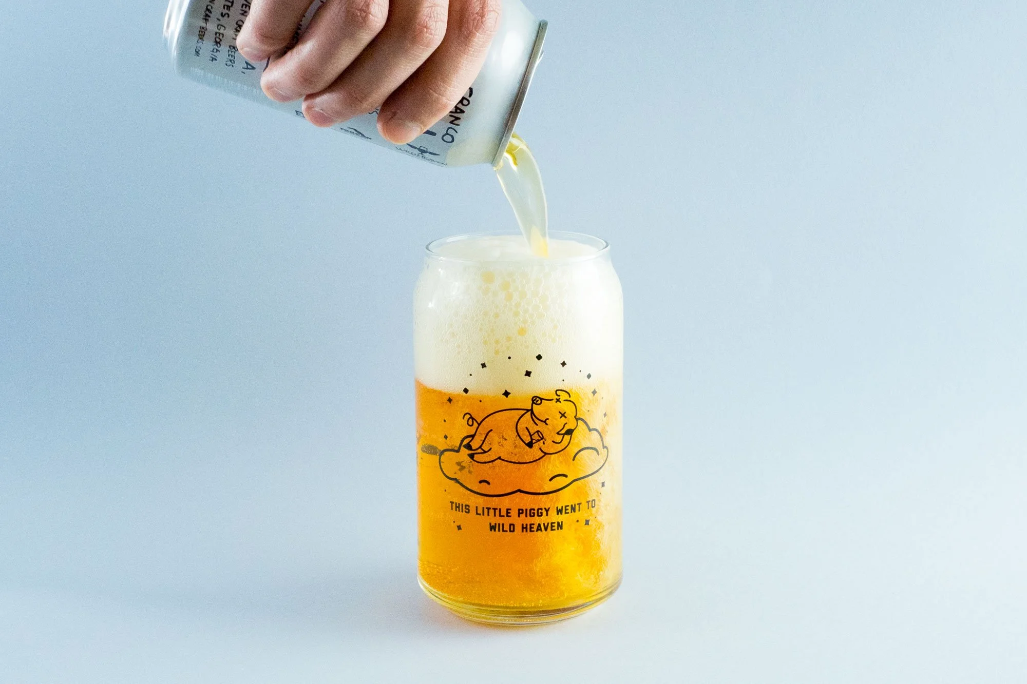 Beer is poured into a glass with an illustration of a pig sleeping, drunk on a cloud with the text saying "This little piggy went to Wild Heaven"