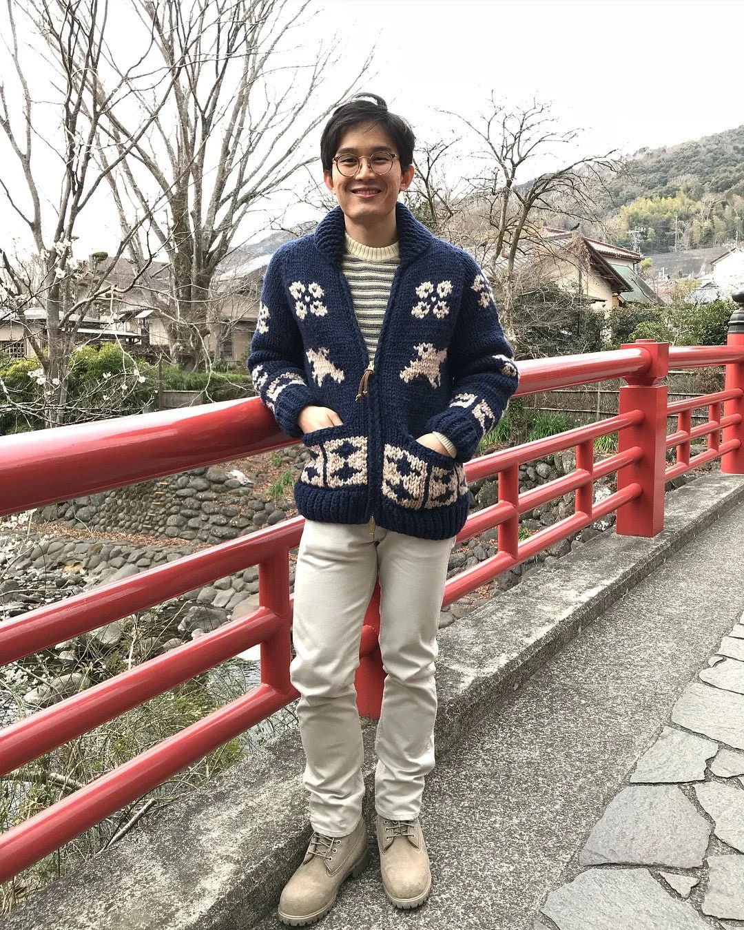 A man stands next to a large red railing wearing the blue swooping designed by Bang. 